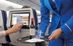 a person holding a tray with a bottle and a glass