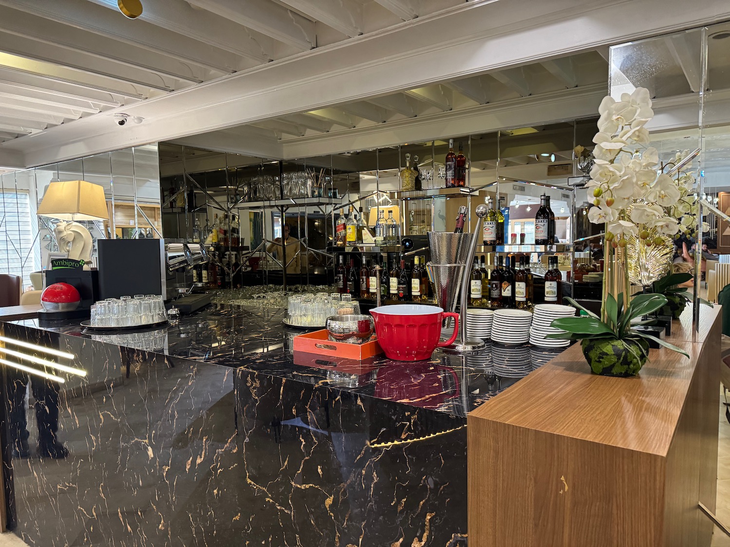 a bar with a mirror and a shelf with glasses and cups