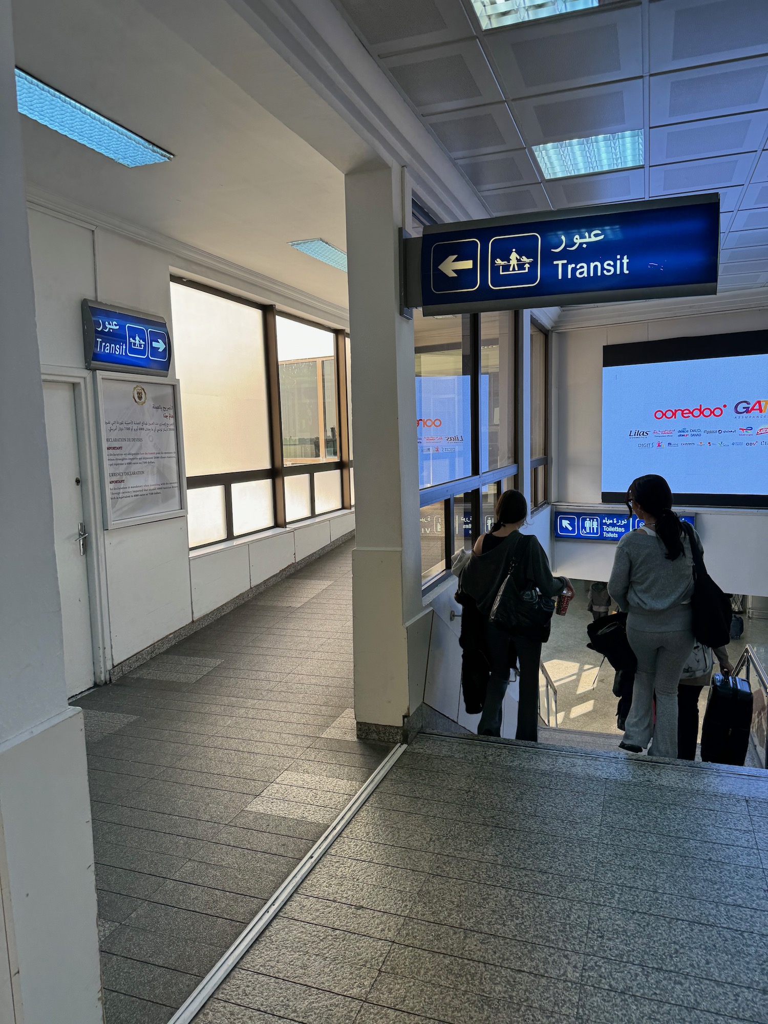 people standing in a hallway with a sign and a screen