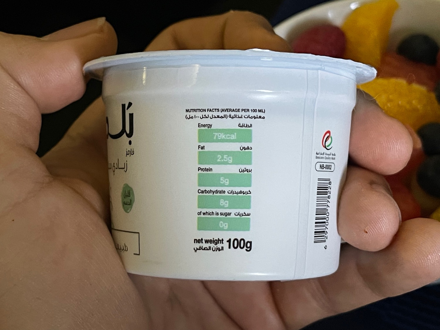 a hand holding a container of yogurt