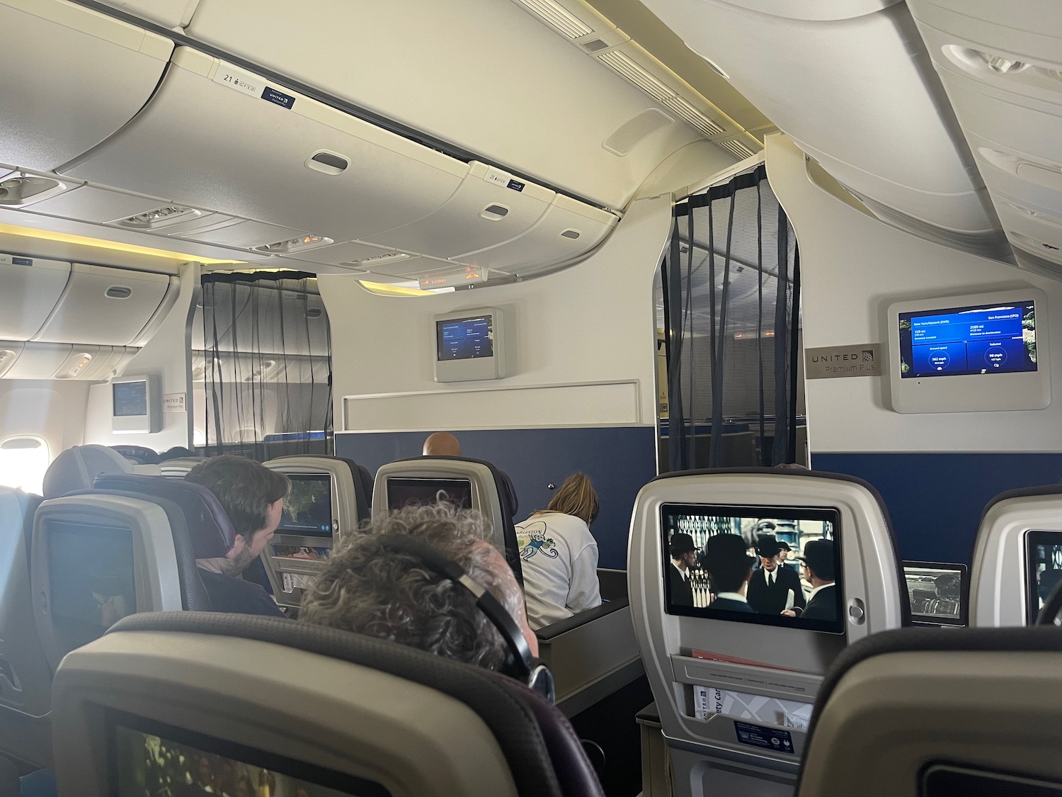 people sitting in an airplane with a group of people watching television