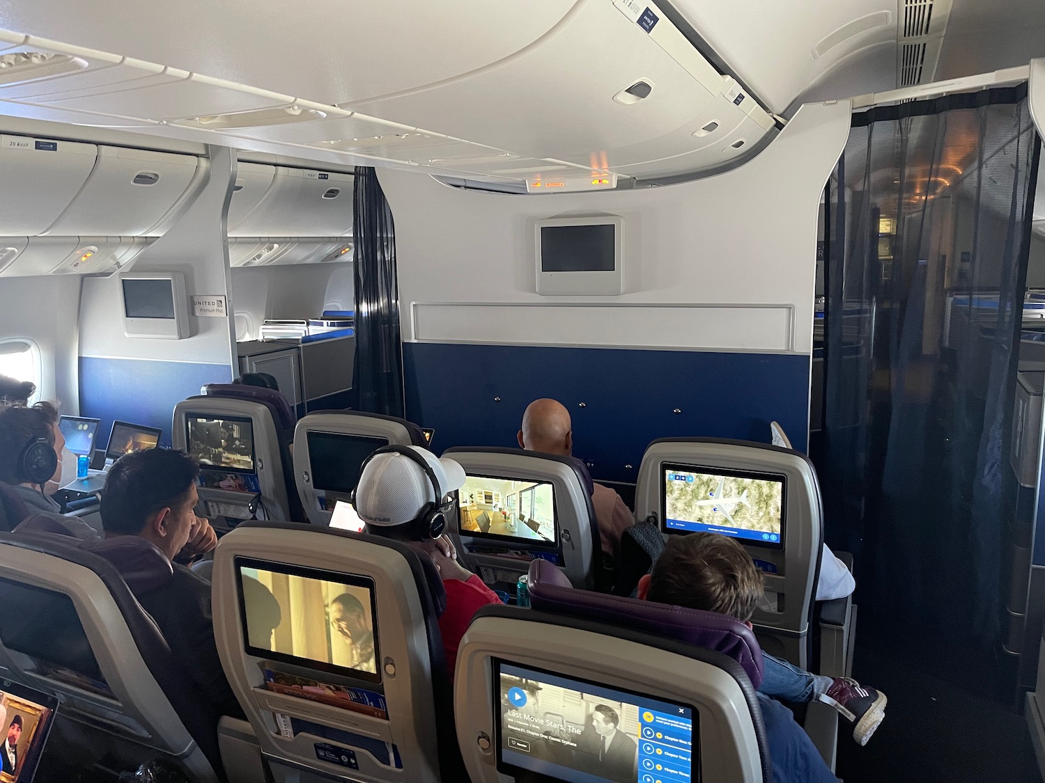 people sitting in an airplane with a group of people watching tv