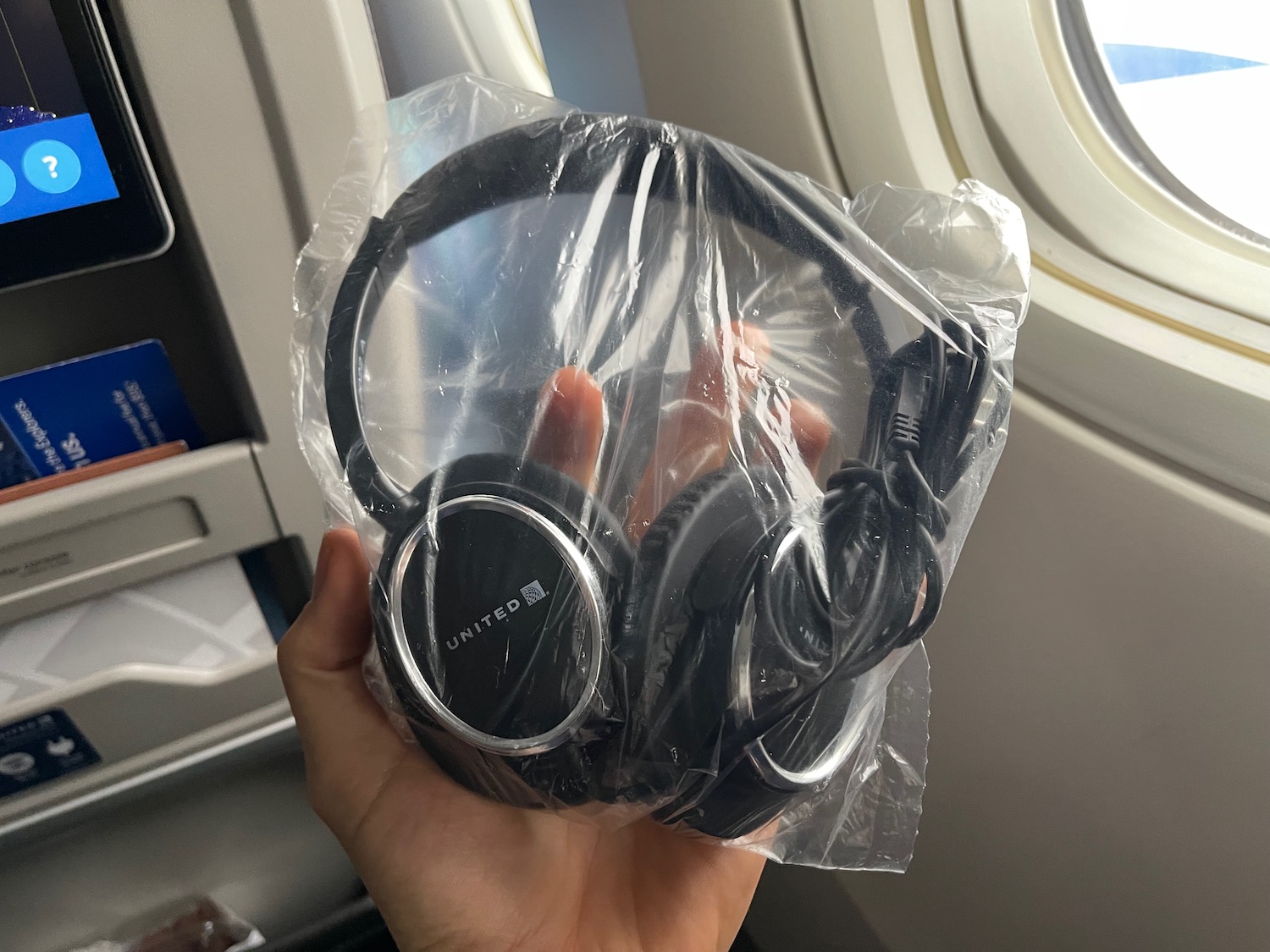 a hand holding a plastic bag of headphones