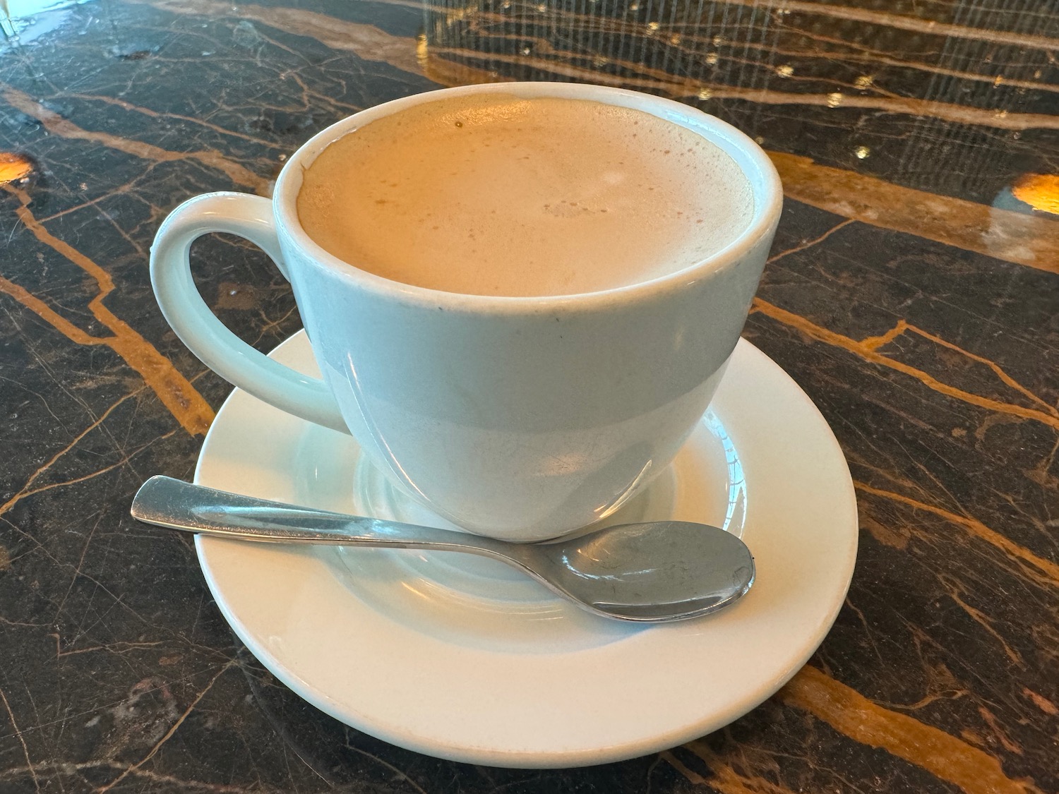 a cup of coffee on a saucer with a spoon