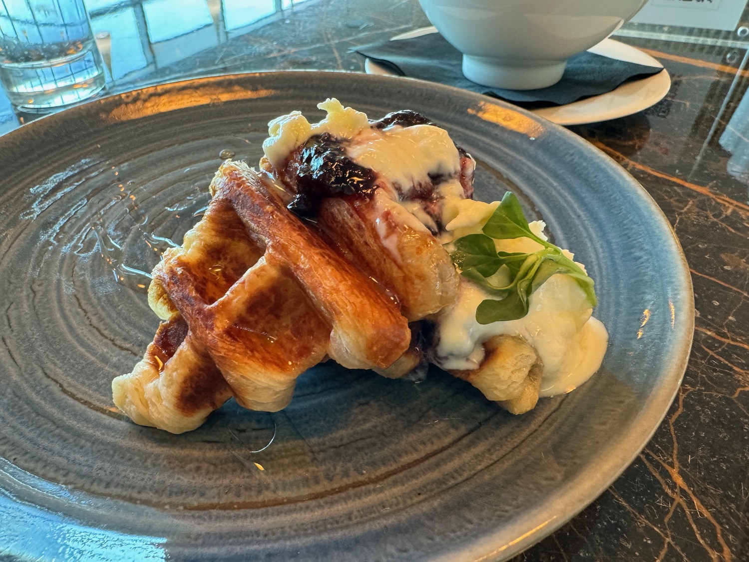 a plate of waffles with cream and jam