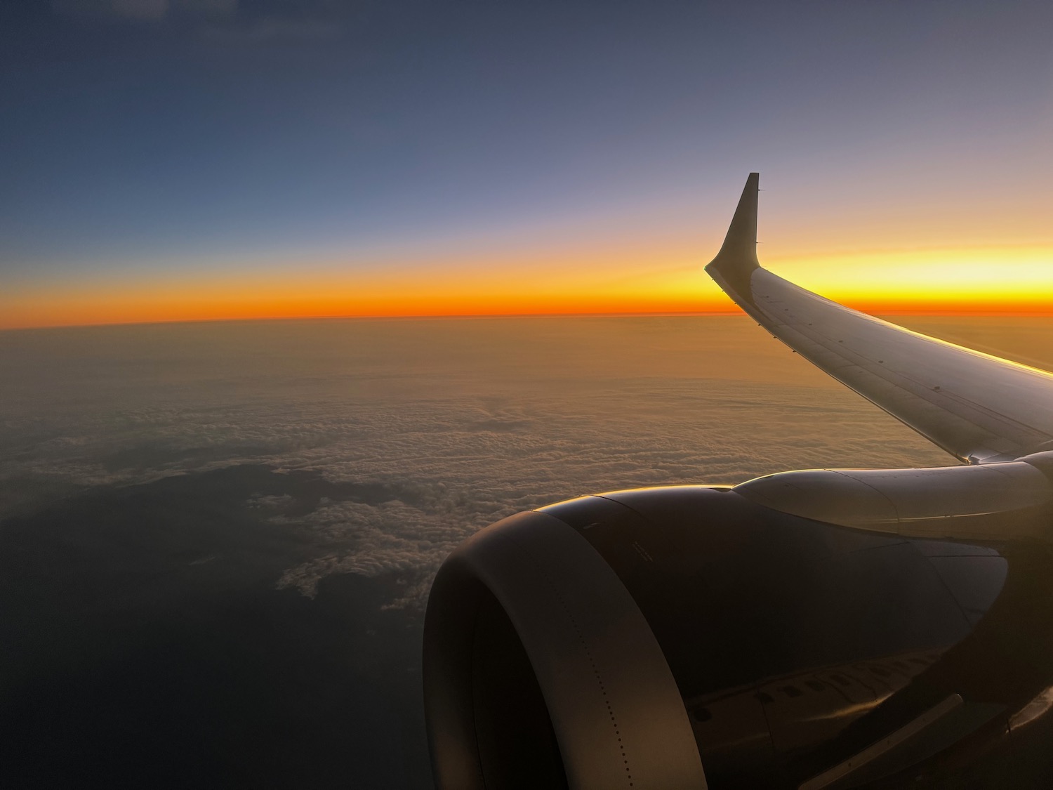 an airplane wing and the sun above the clouds