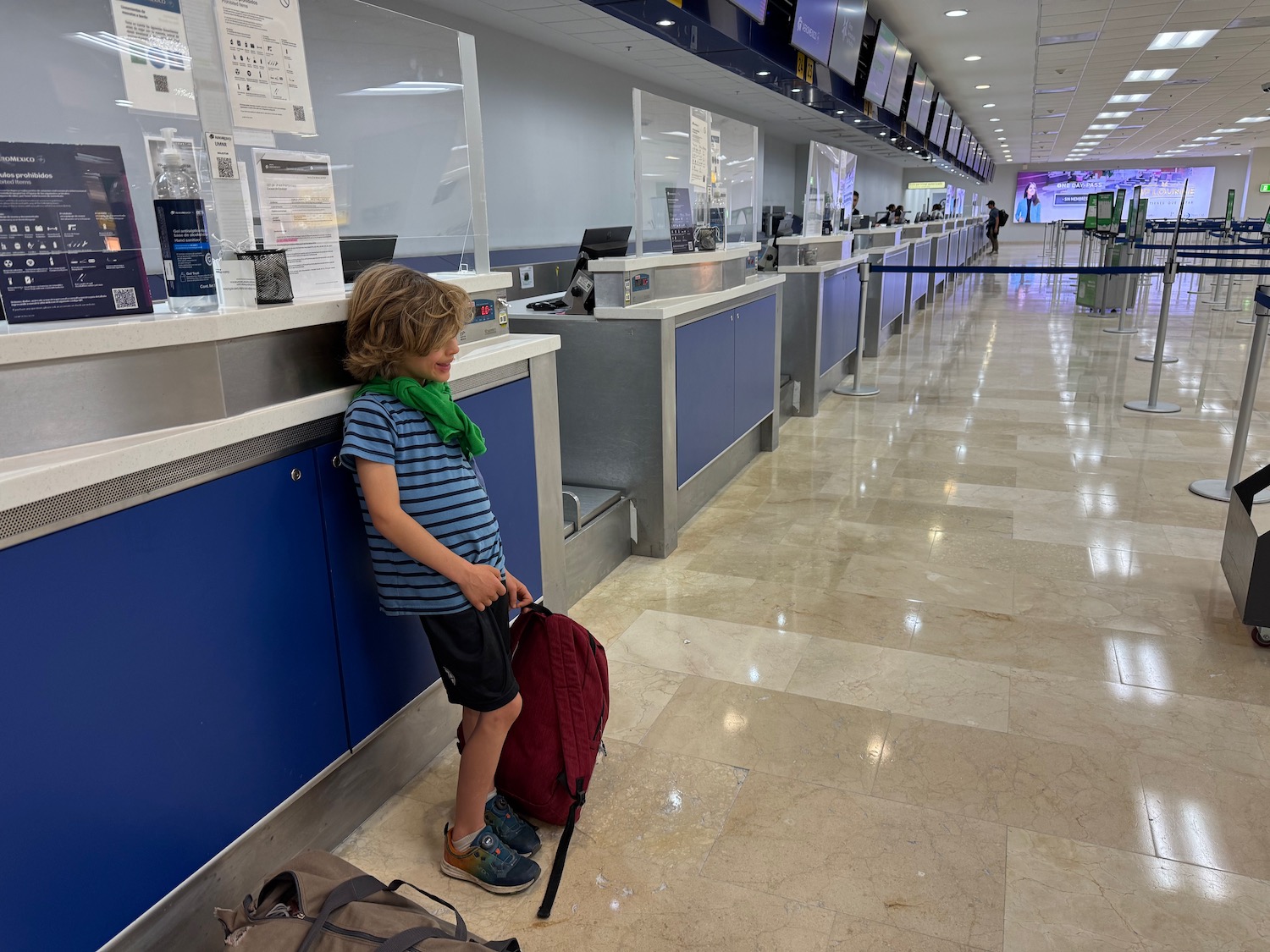 a child leaning against a counter in a airport