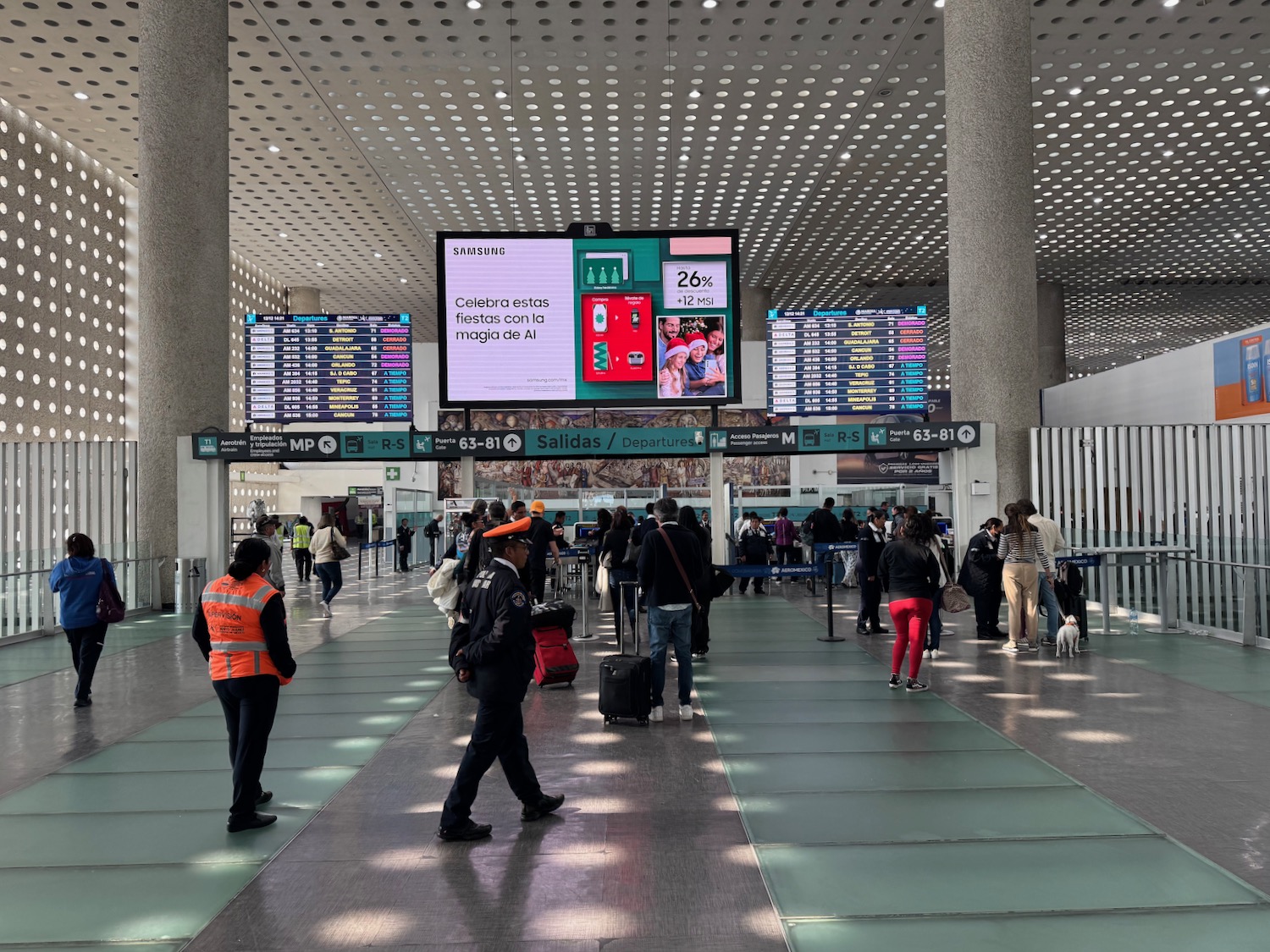 people in an airport with a large screen