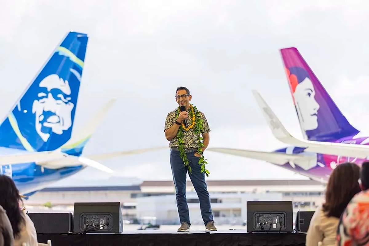 a man wearing a lei on a stage with airplanes in the background