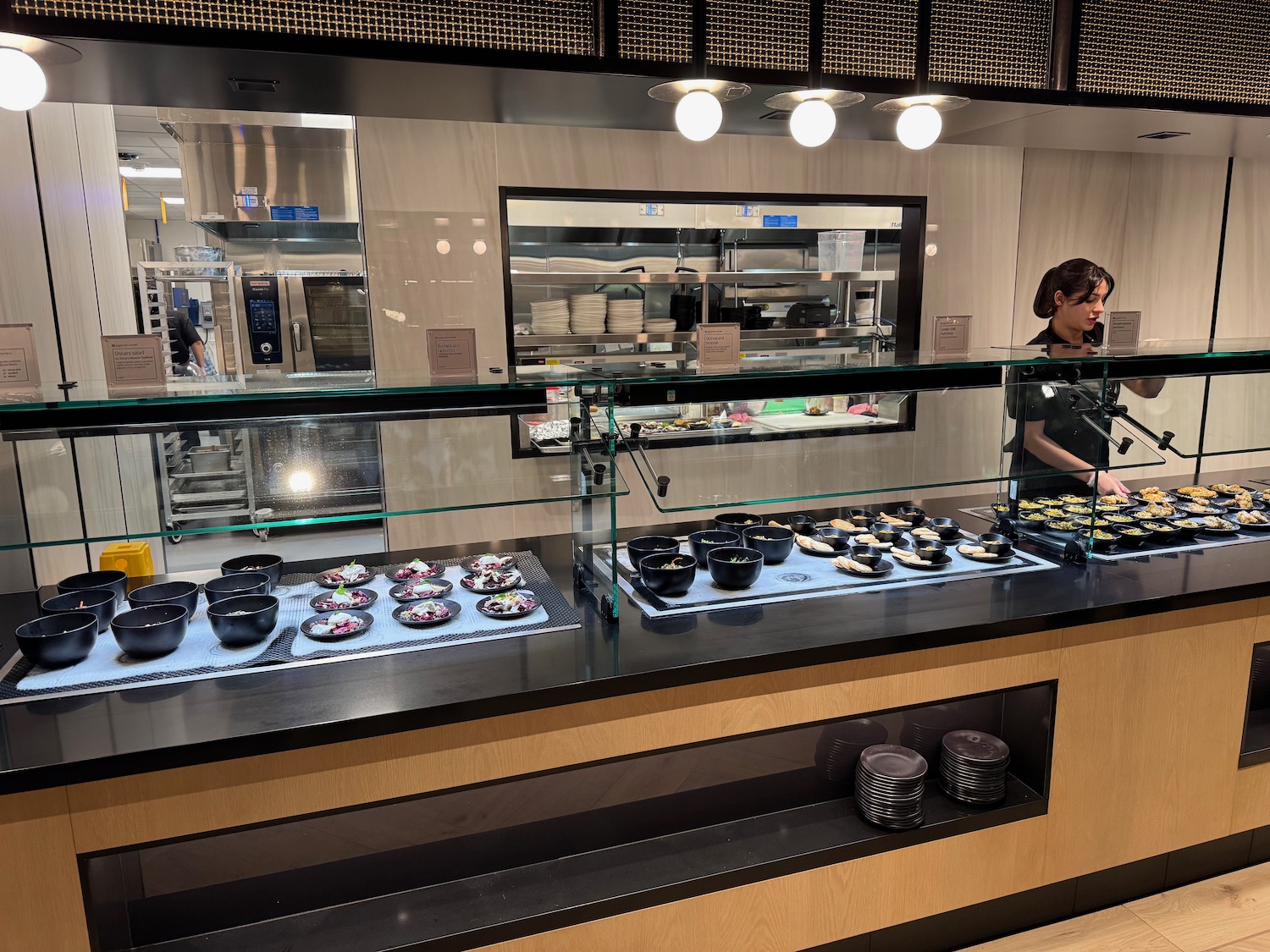 a woman standing behind a counter with food on it