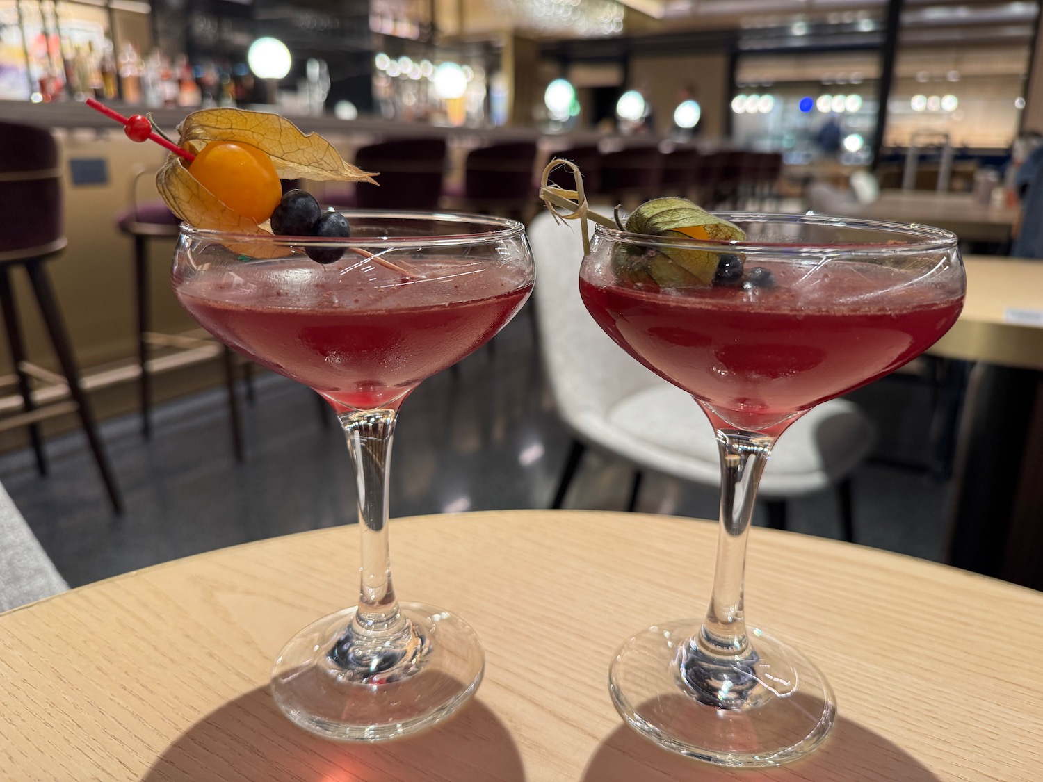 two glasses of pink liquid with fruit on top