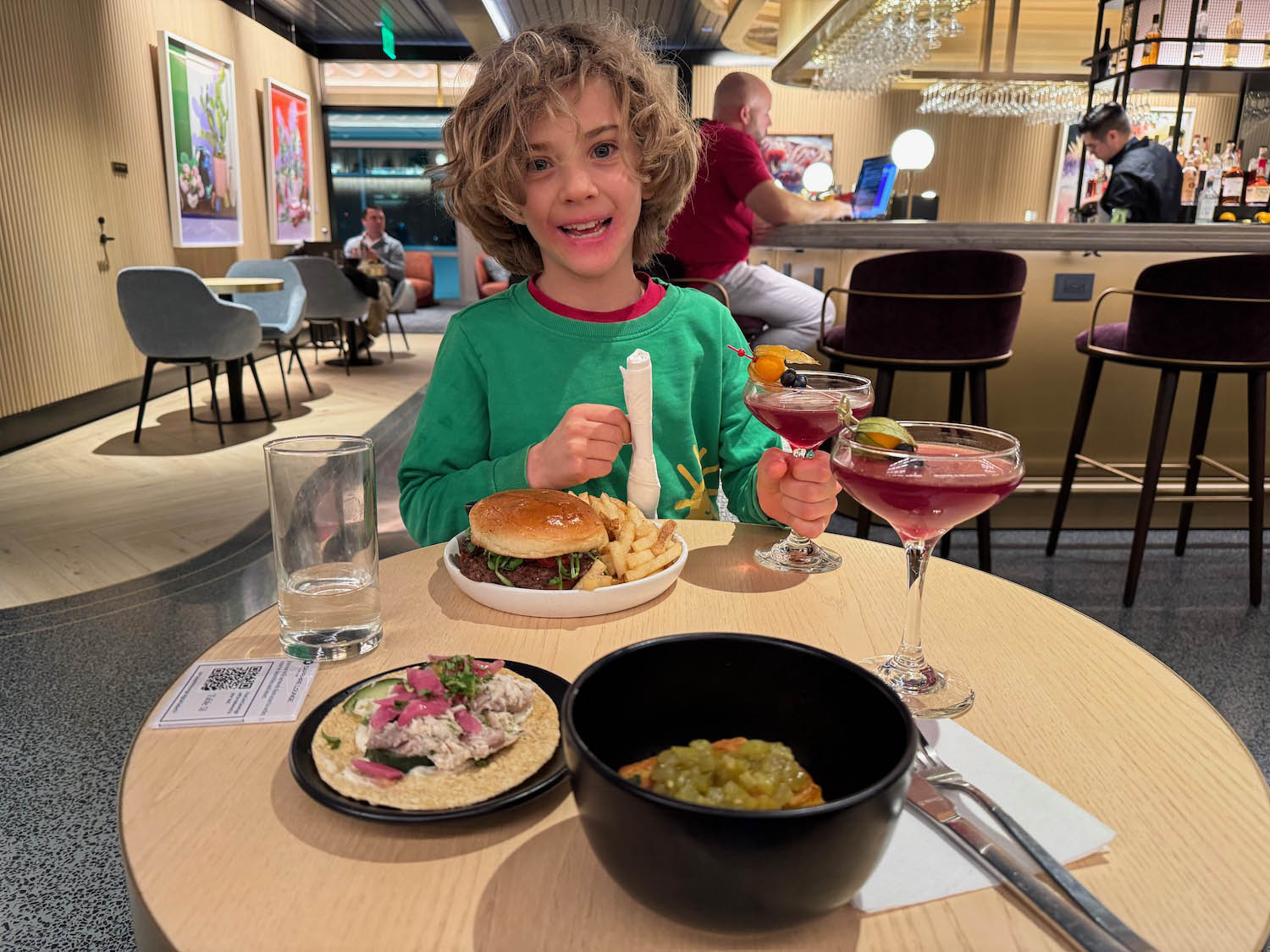 a child sitting at a table with food and drinks