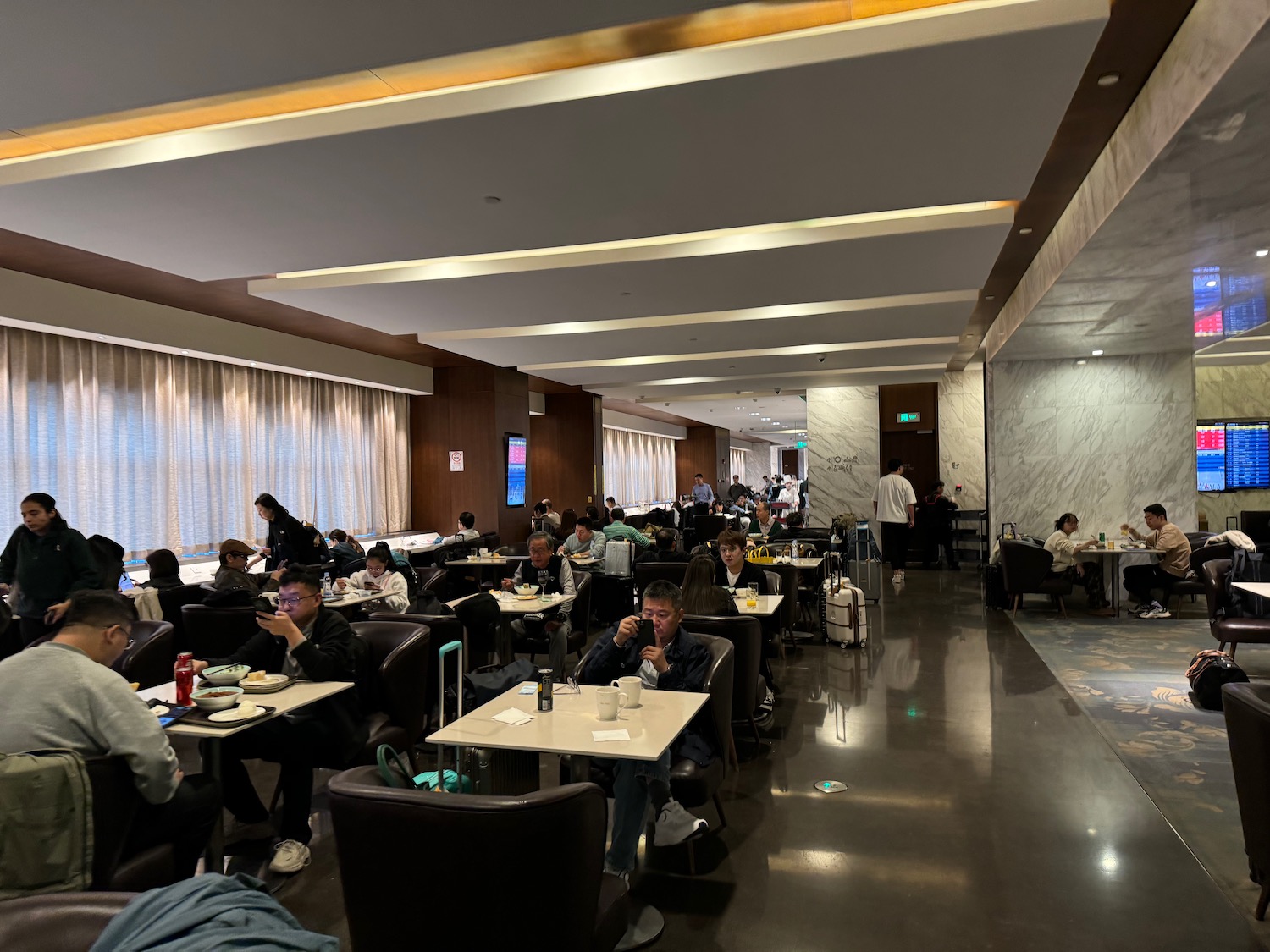 a group of people sitting at tables in a room with white curtains