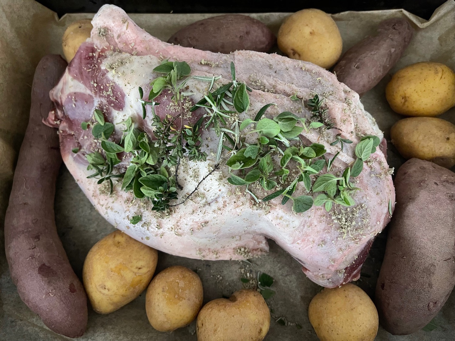 a piece of meat with herbs on top of potatoes