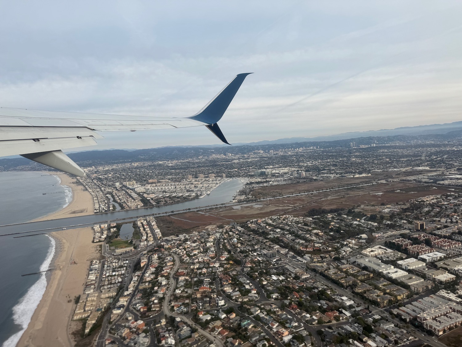 an airplane wing and city view from the airplane window