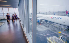 people standing in a terminal with a plane in the background