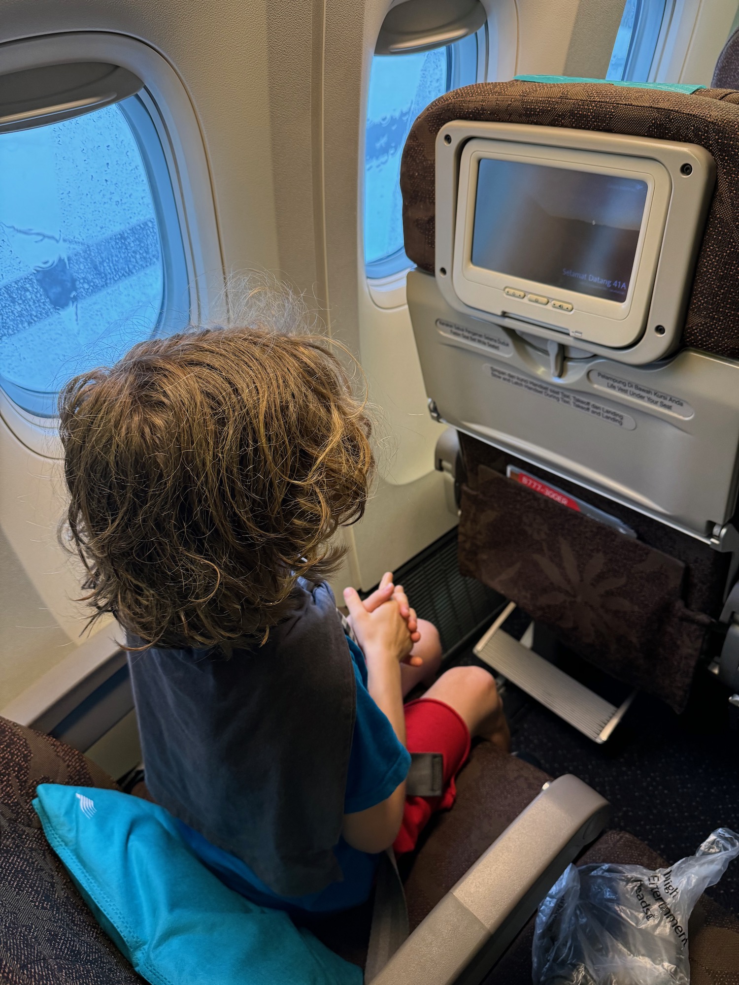 a child looking out a window on an airplane