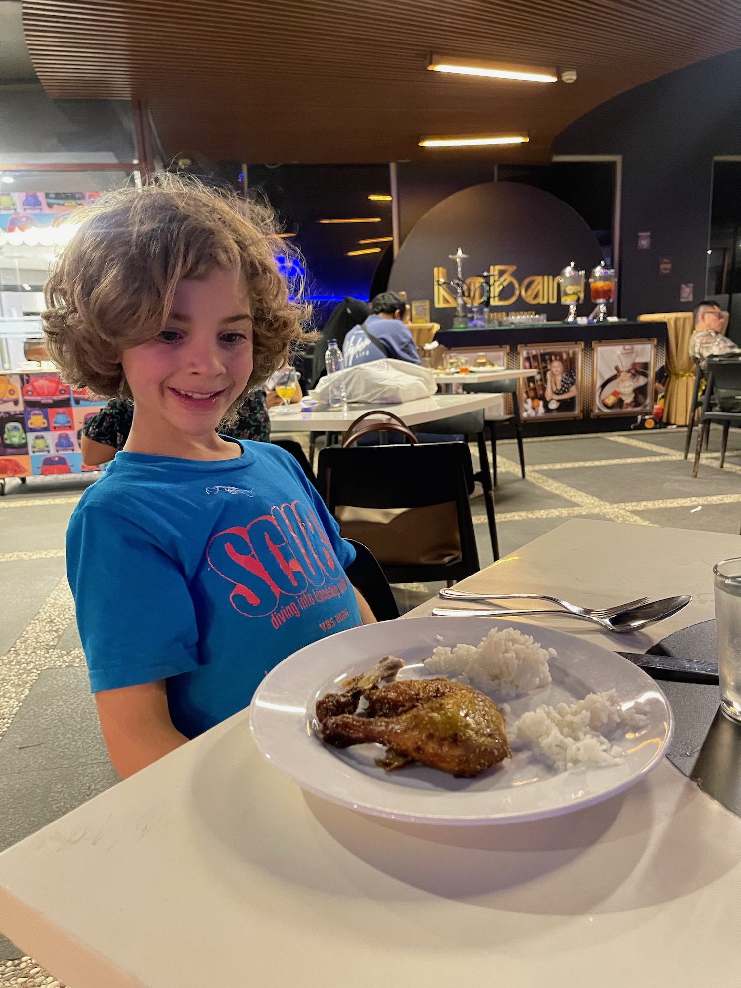 a child sitting at a table with a plate of food