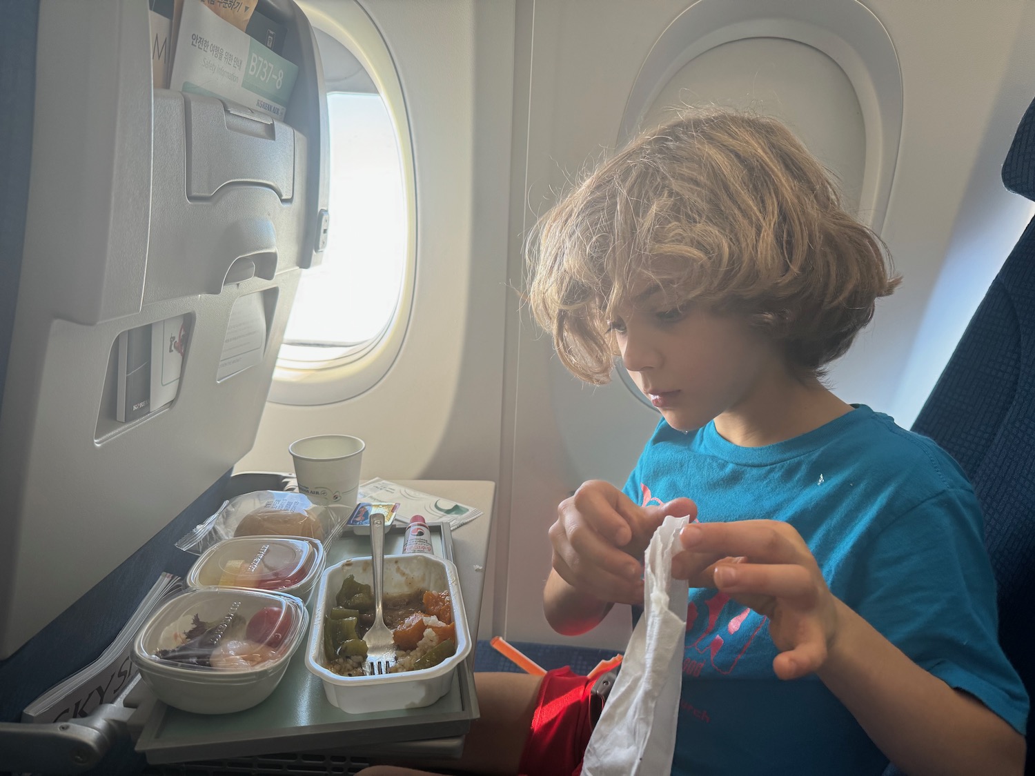 a boy sitting in an airplane eating food