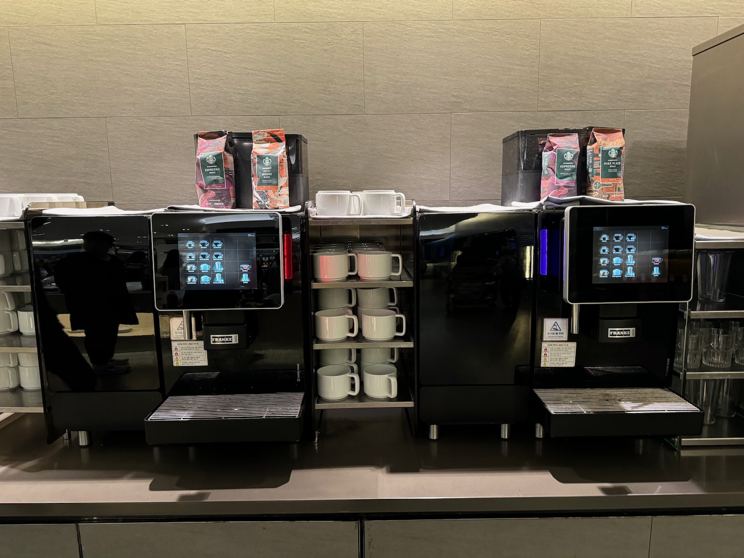 a group of coffee machines with cups on top