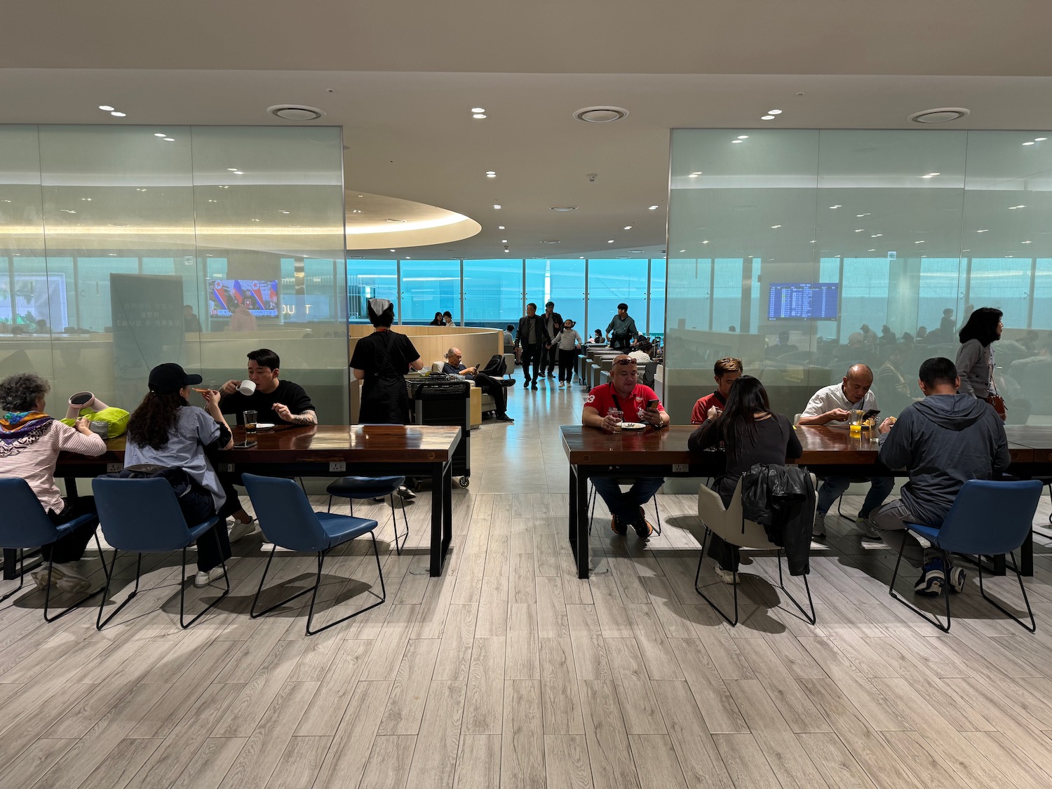 a group of people sitting at tables in a room with glass walls