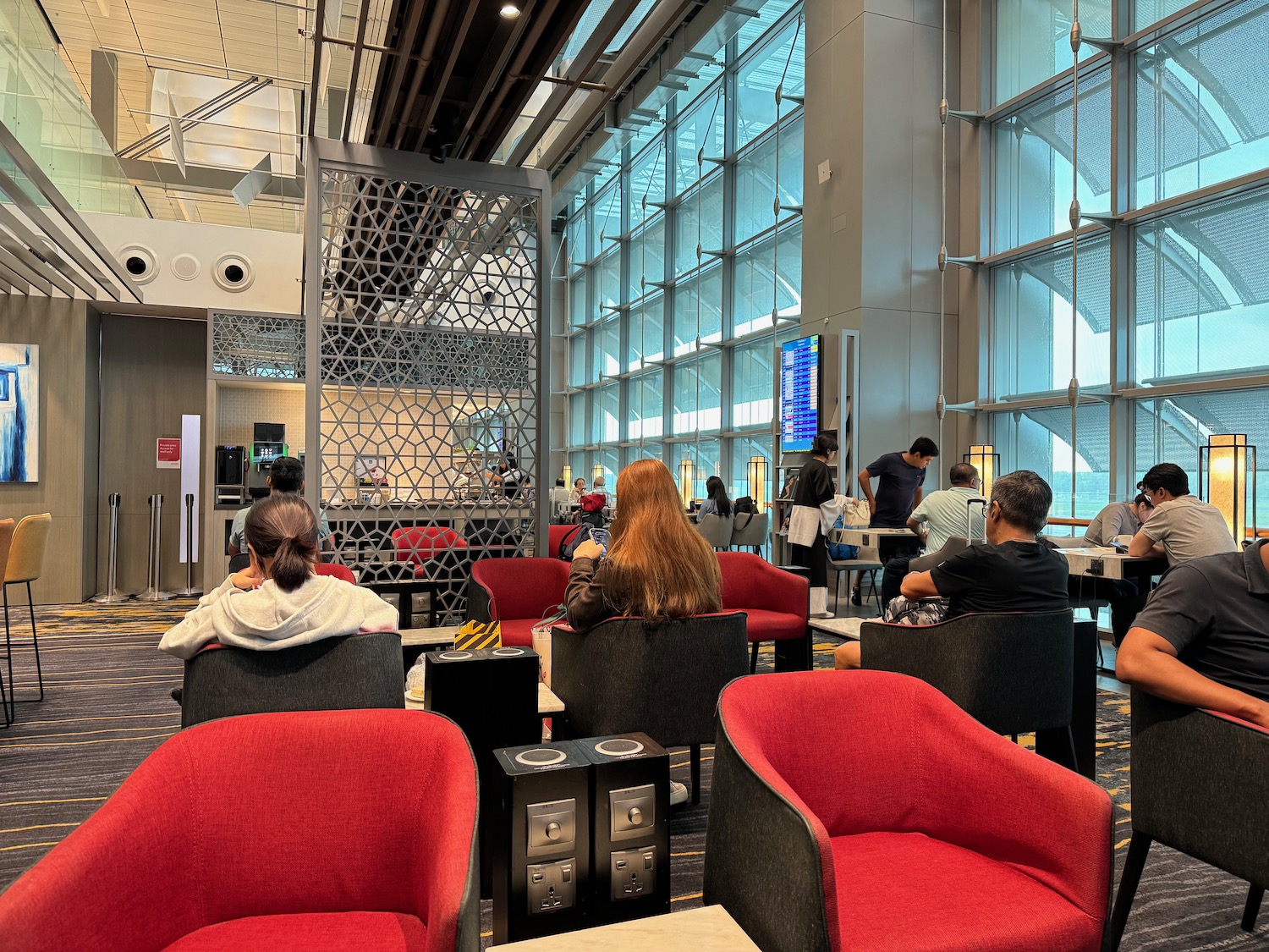 people sitting in chairs in a room with large windows