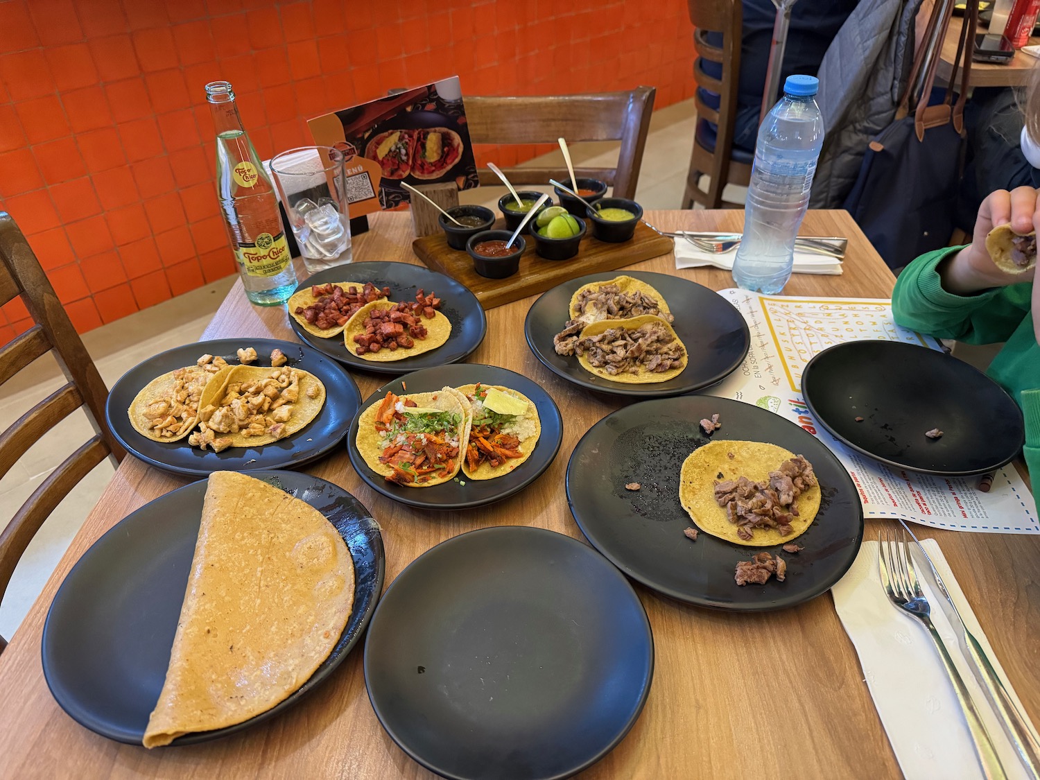 a table with plates of tacos and a bottle of water