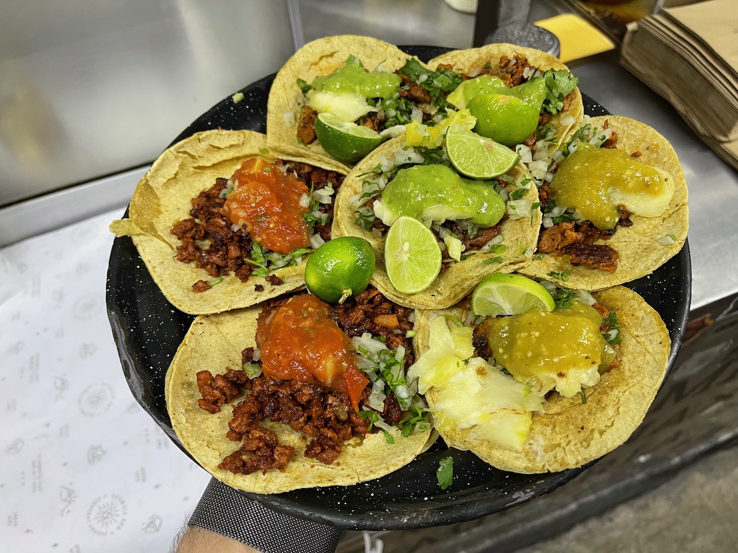 a plate of tacos with limes and sauces