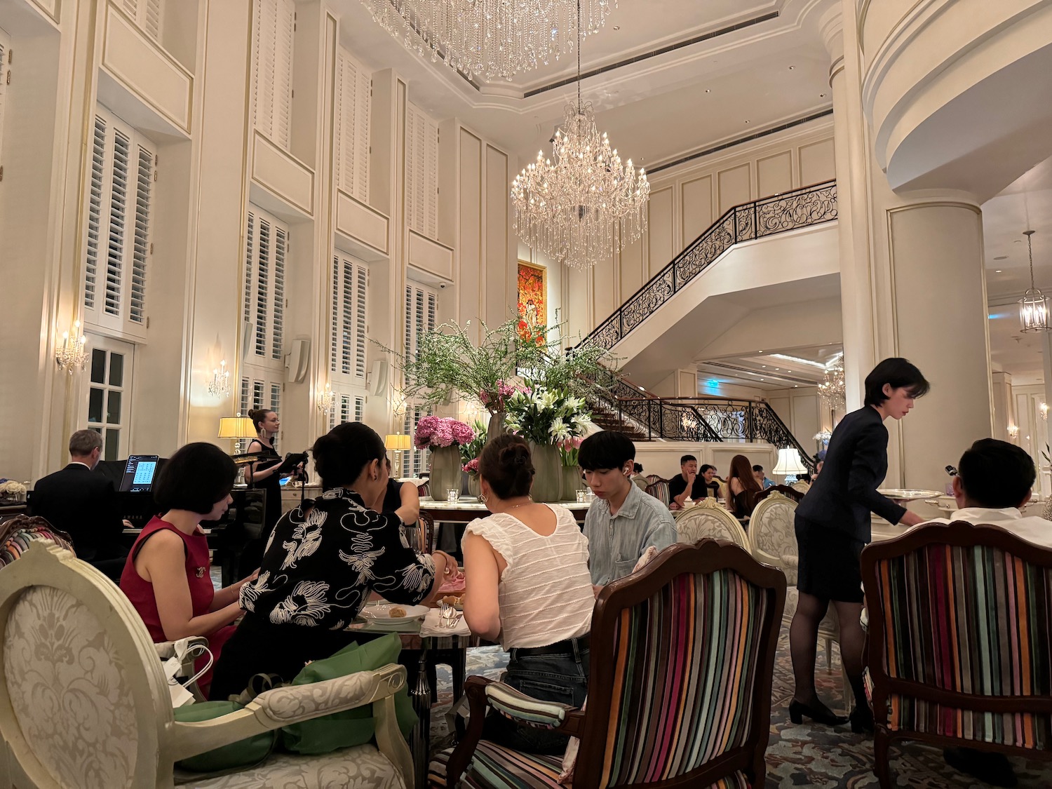 a group of people sitting at tables in a room with chandeliers