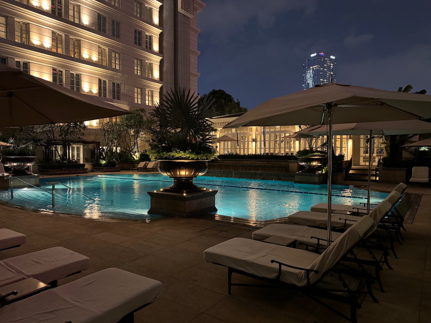 a pool with chairs and umbrellas in front of a building