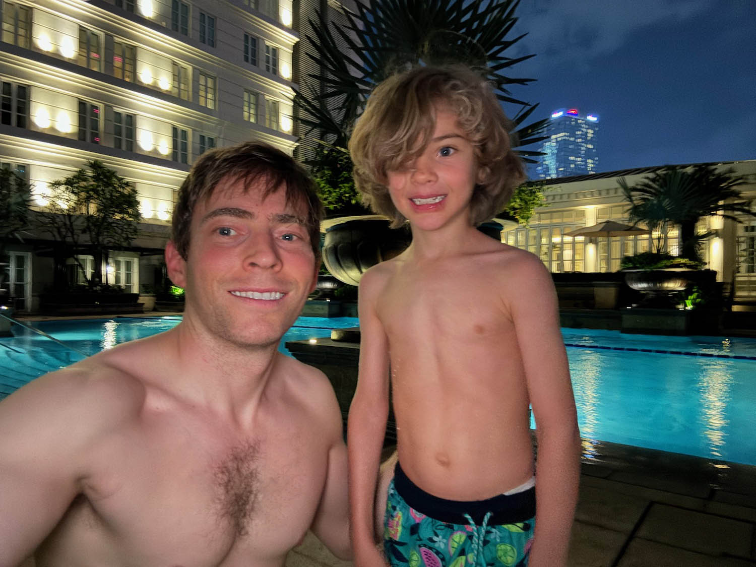 a man and boy taking a selfie by a pool