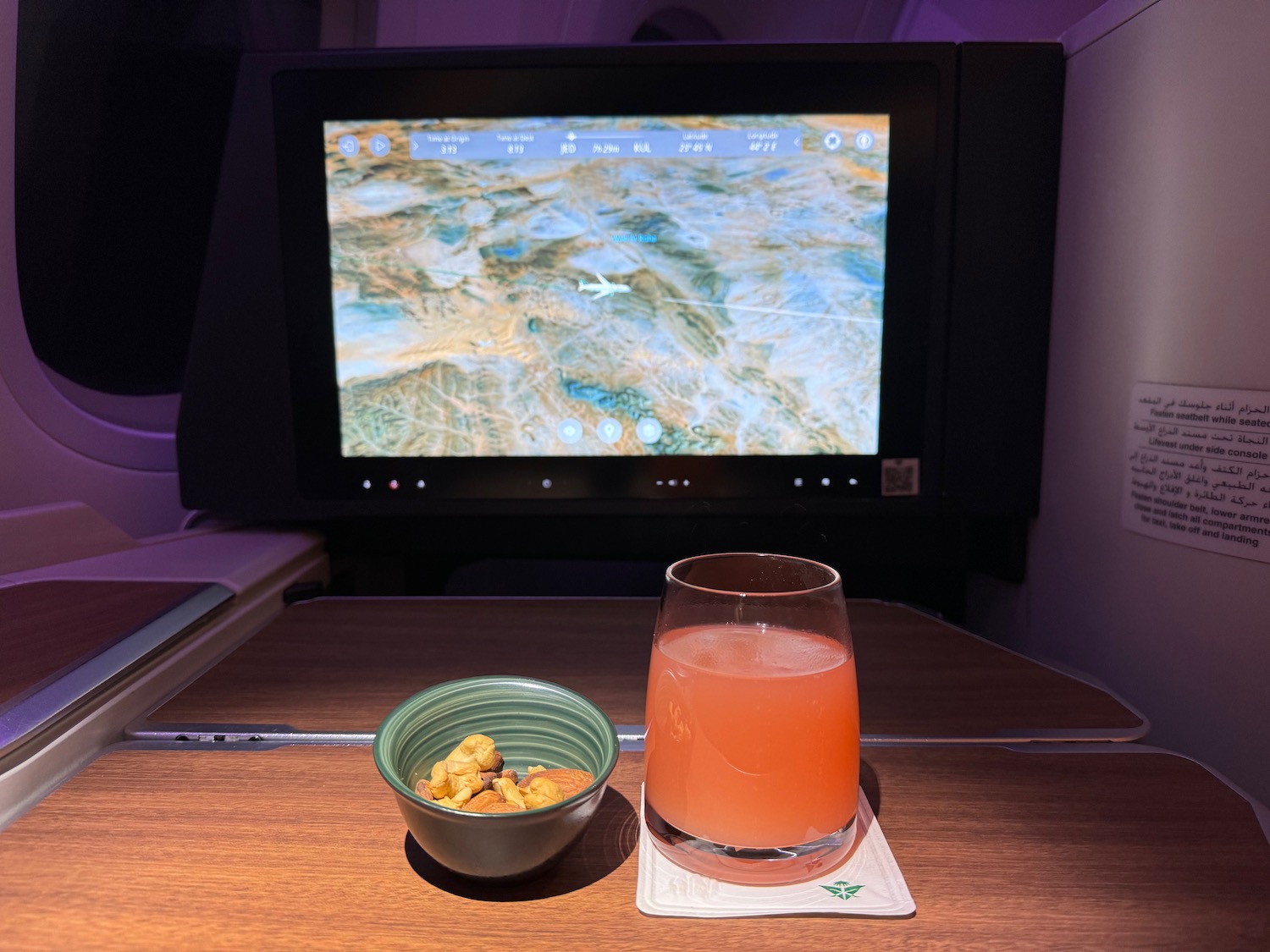 a glass of drink and bowl of cereal on a table with a television