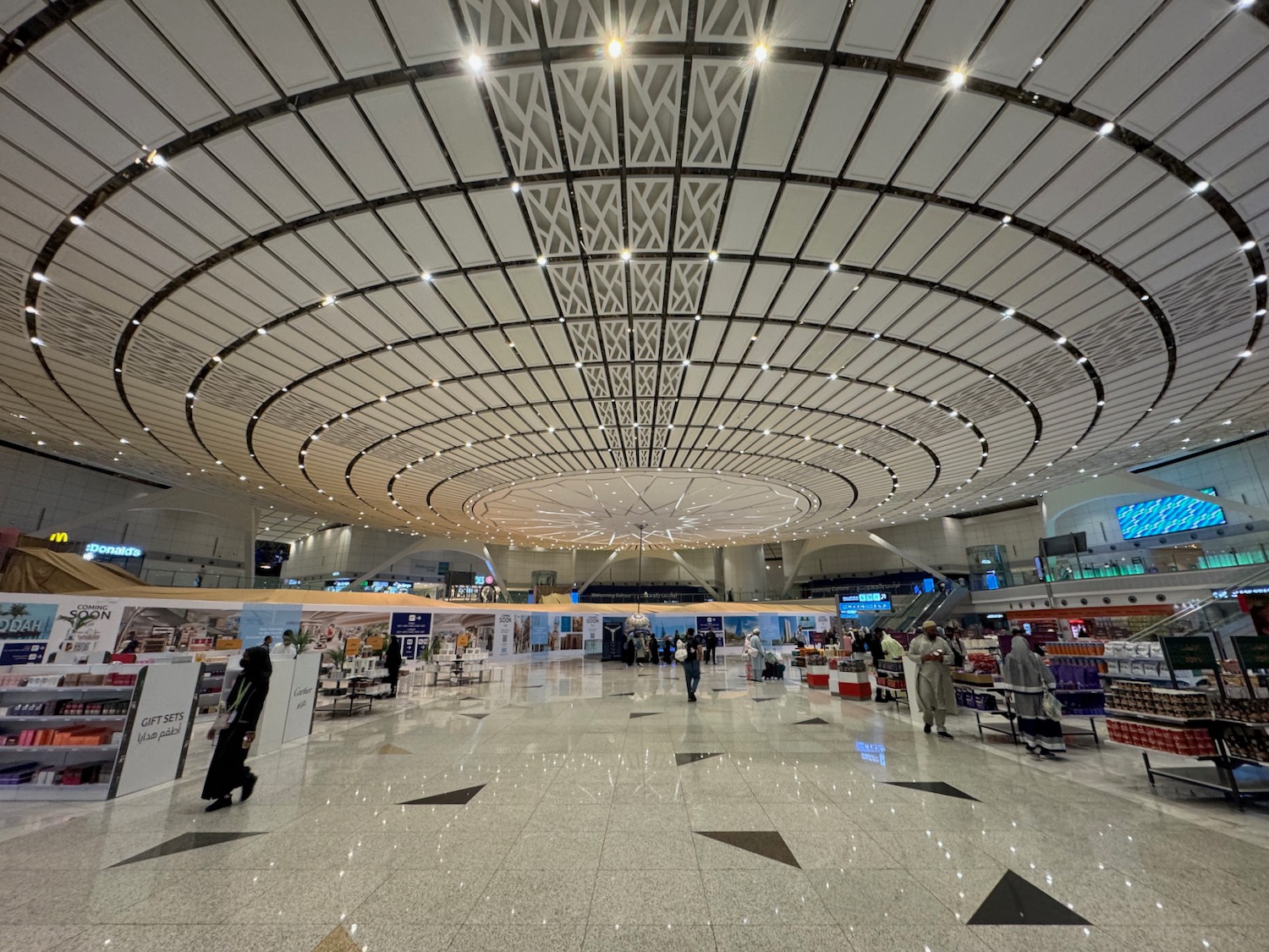 a large white and black tiled floor with people walking in it