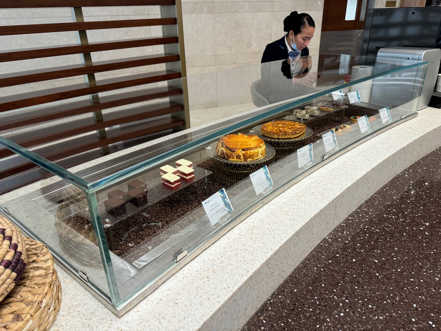 a woman standing behind a glass case with food on it