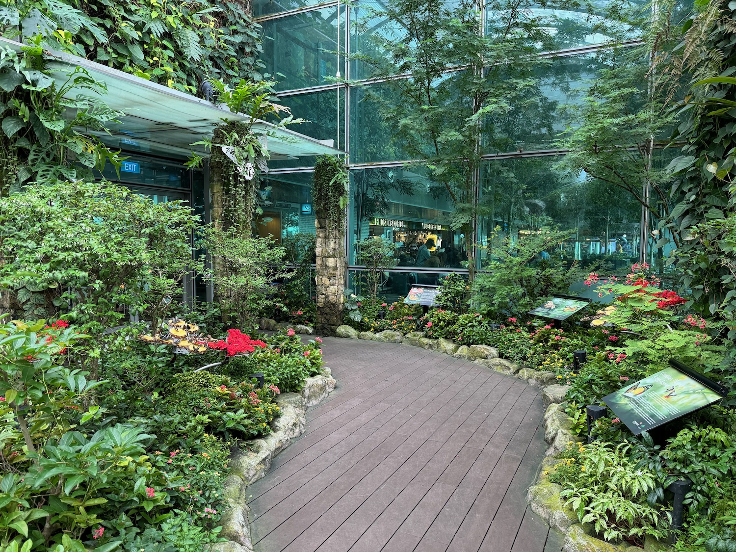 a walkway inside a building with plants and trees