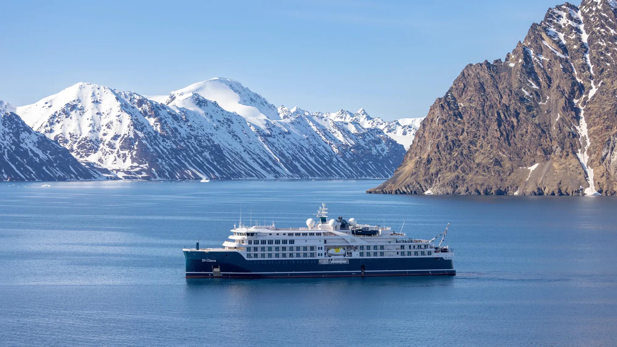 a ship in the water with mountains in the background