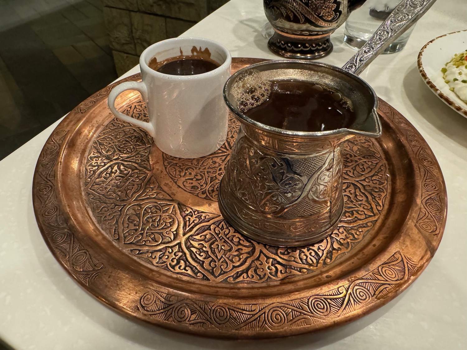 a copper tray with a cup and a pitcher of coffee on it