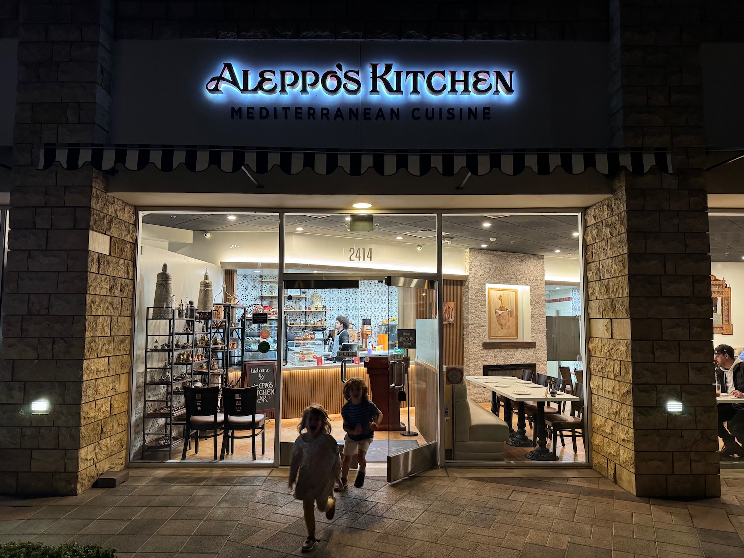 a two children running in front of a restaurant