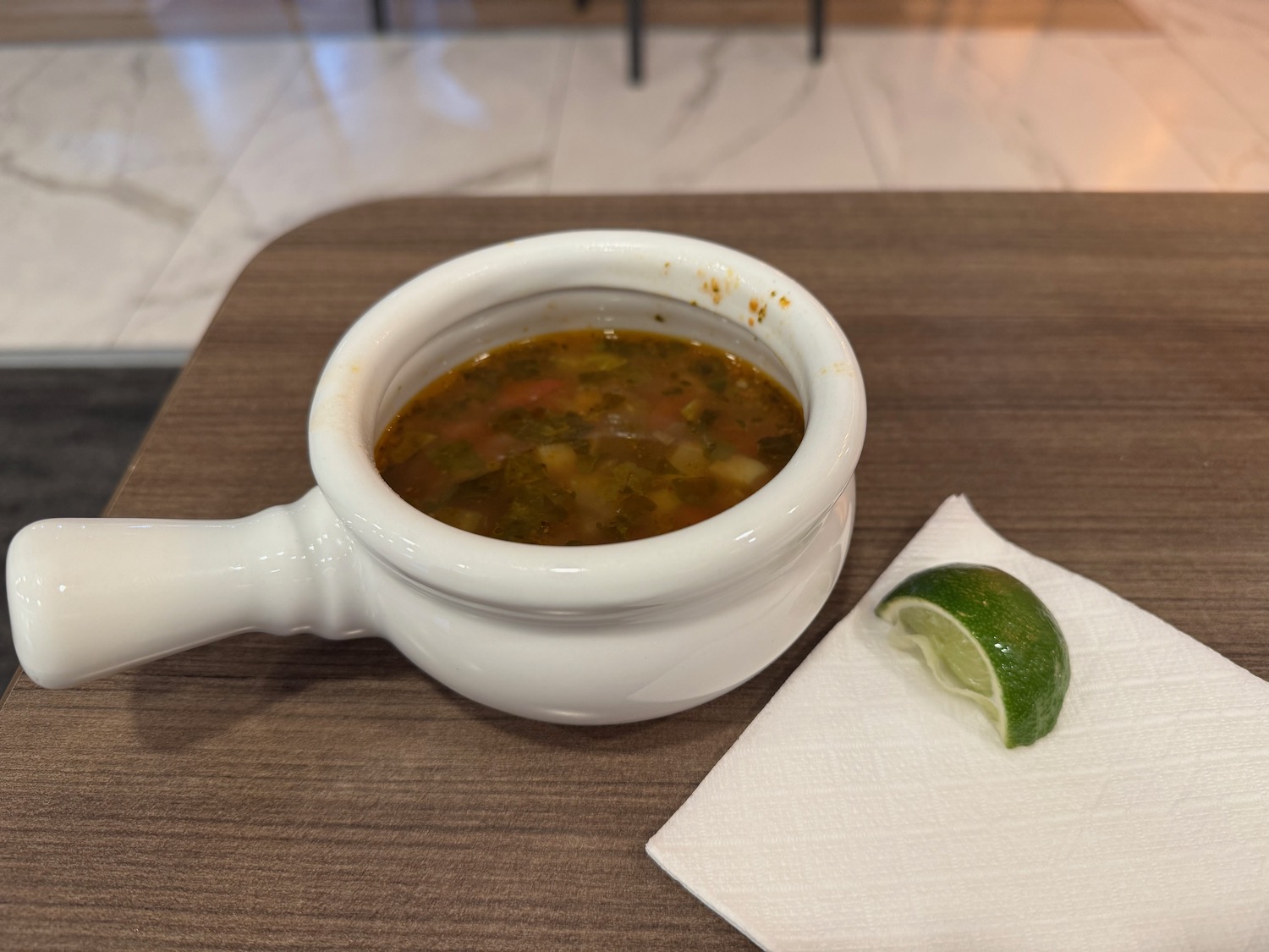 a bowl of soup with a lime wedge on a napkin