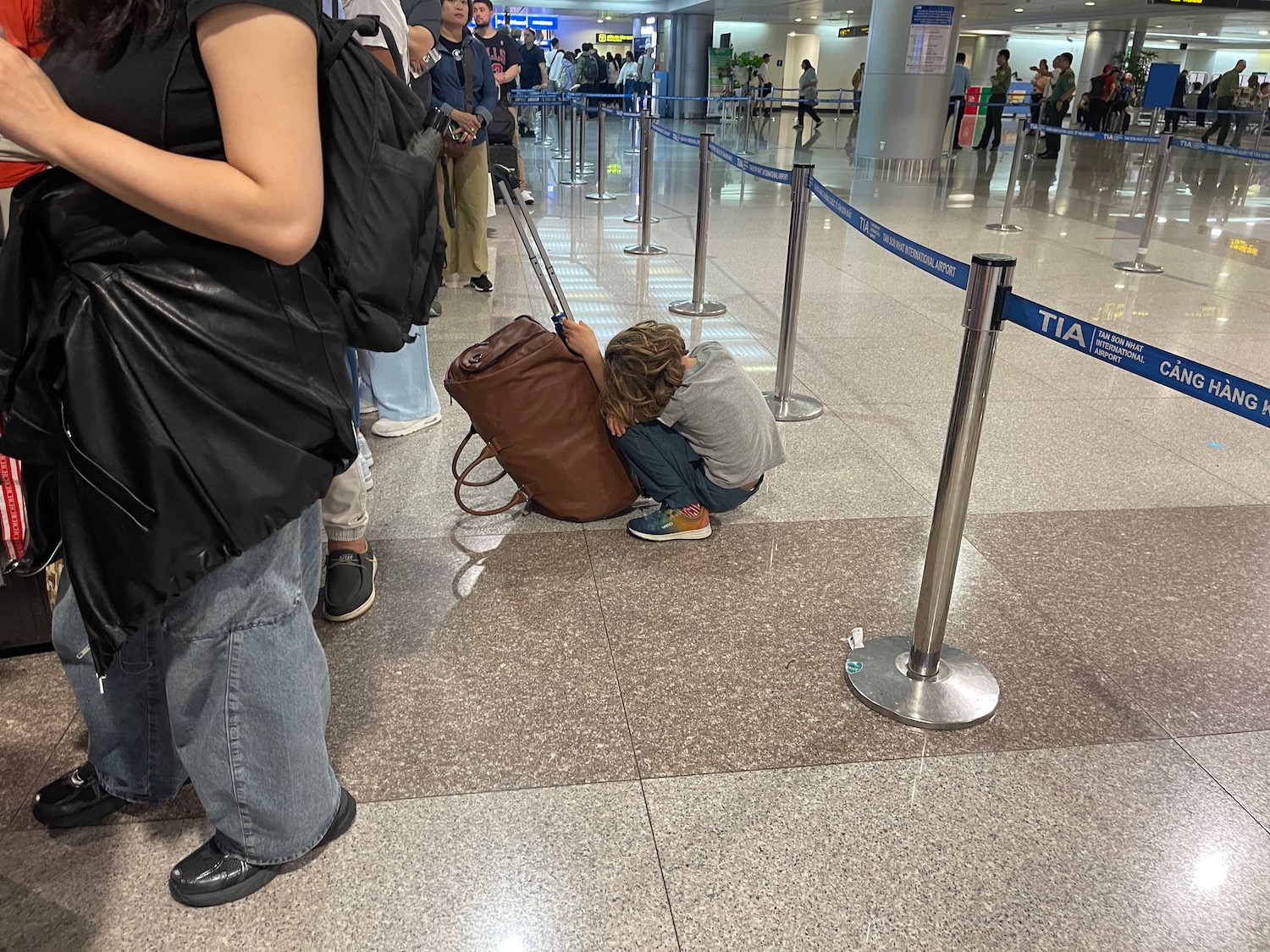 a boy kneeling on the ground with a luggage bag