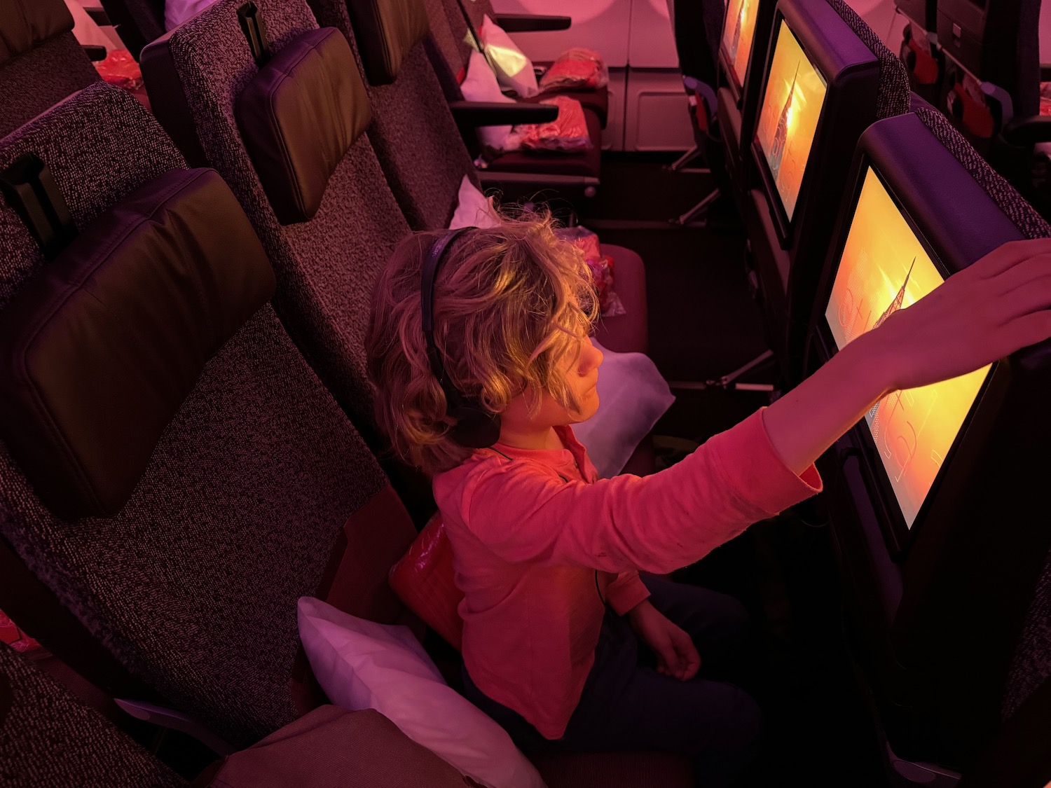 a child sitting in an airplane with a screen