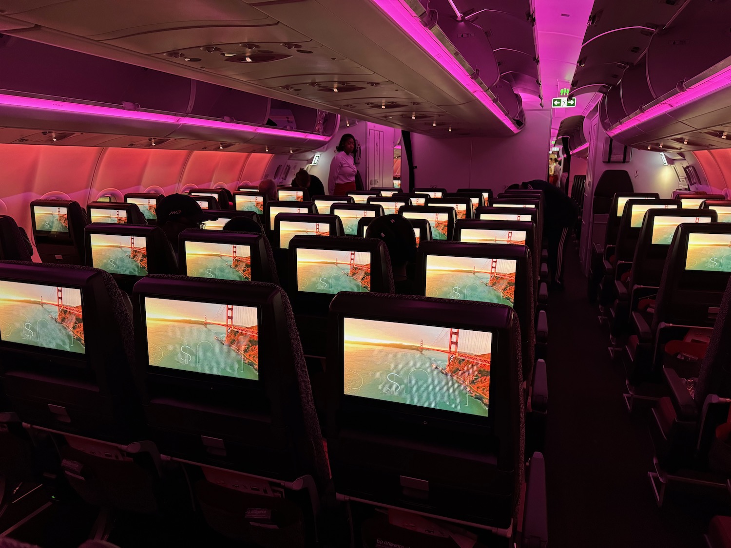 a row of seats with monitors on the back of the plane