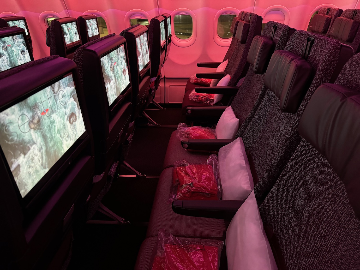 a row of seats with monitors on the side of the plane