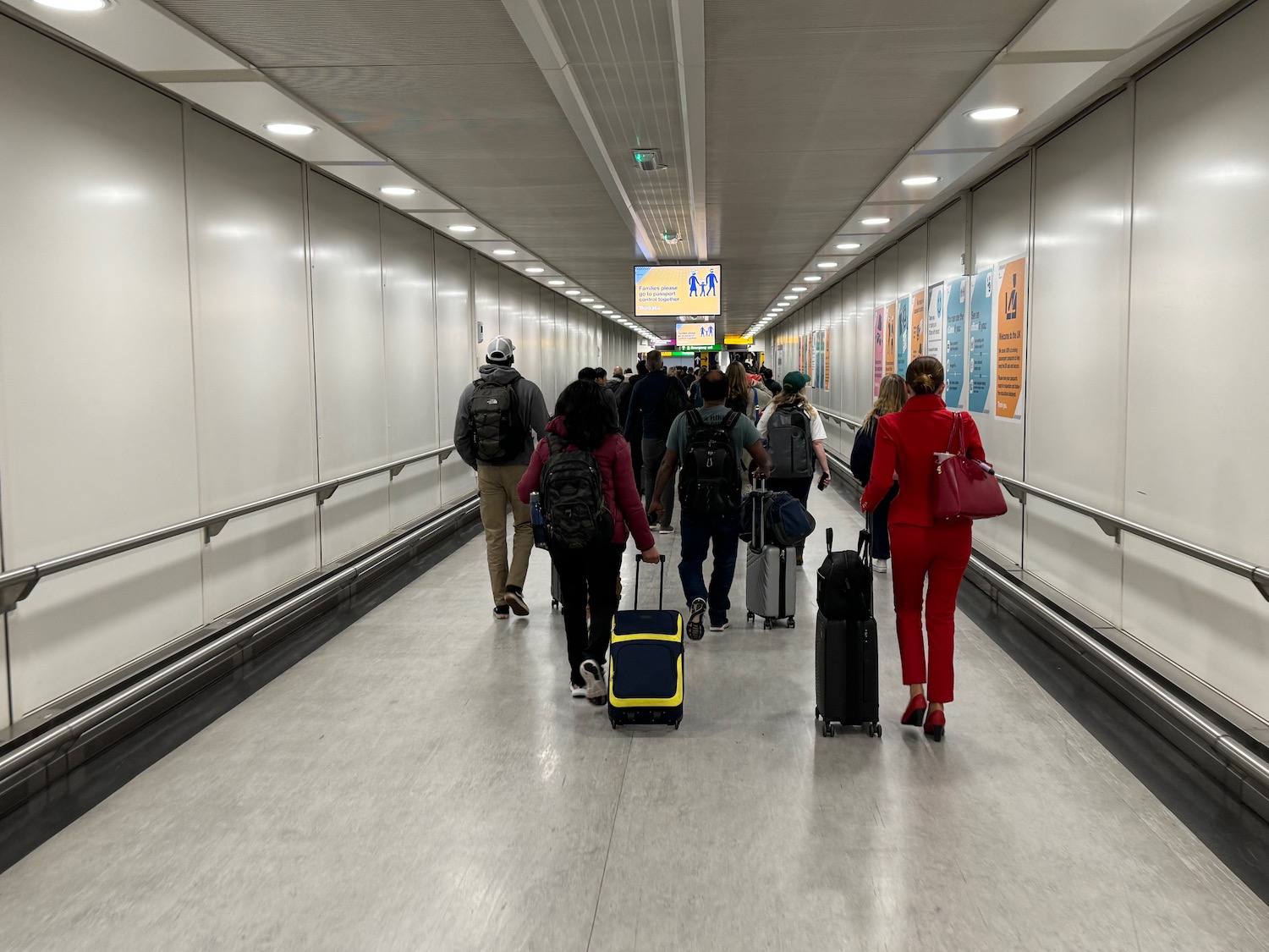 a group of people walking in a hallway with luggage