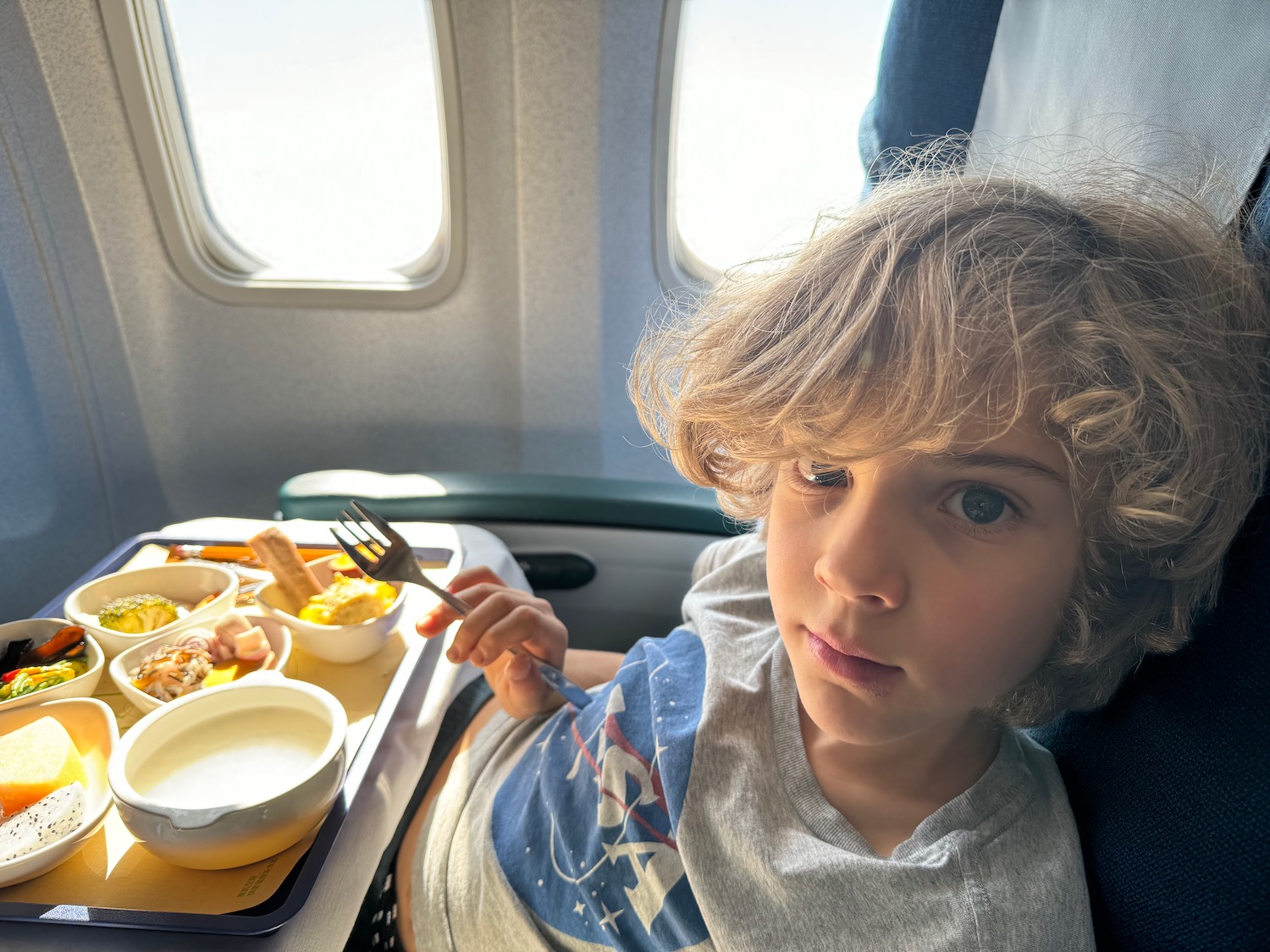 a child sitting in a chair with food in front of him