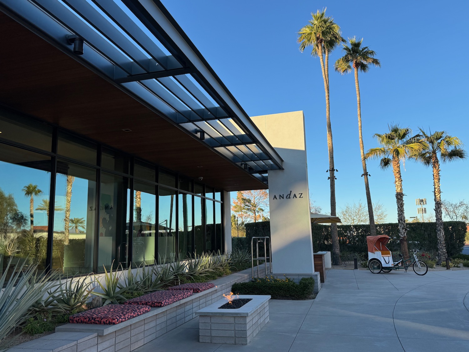 a building with a fire pit and palm trees