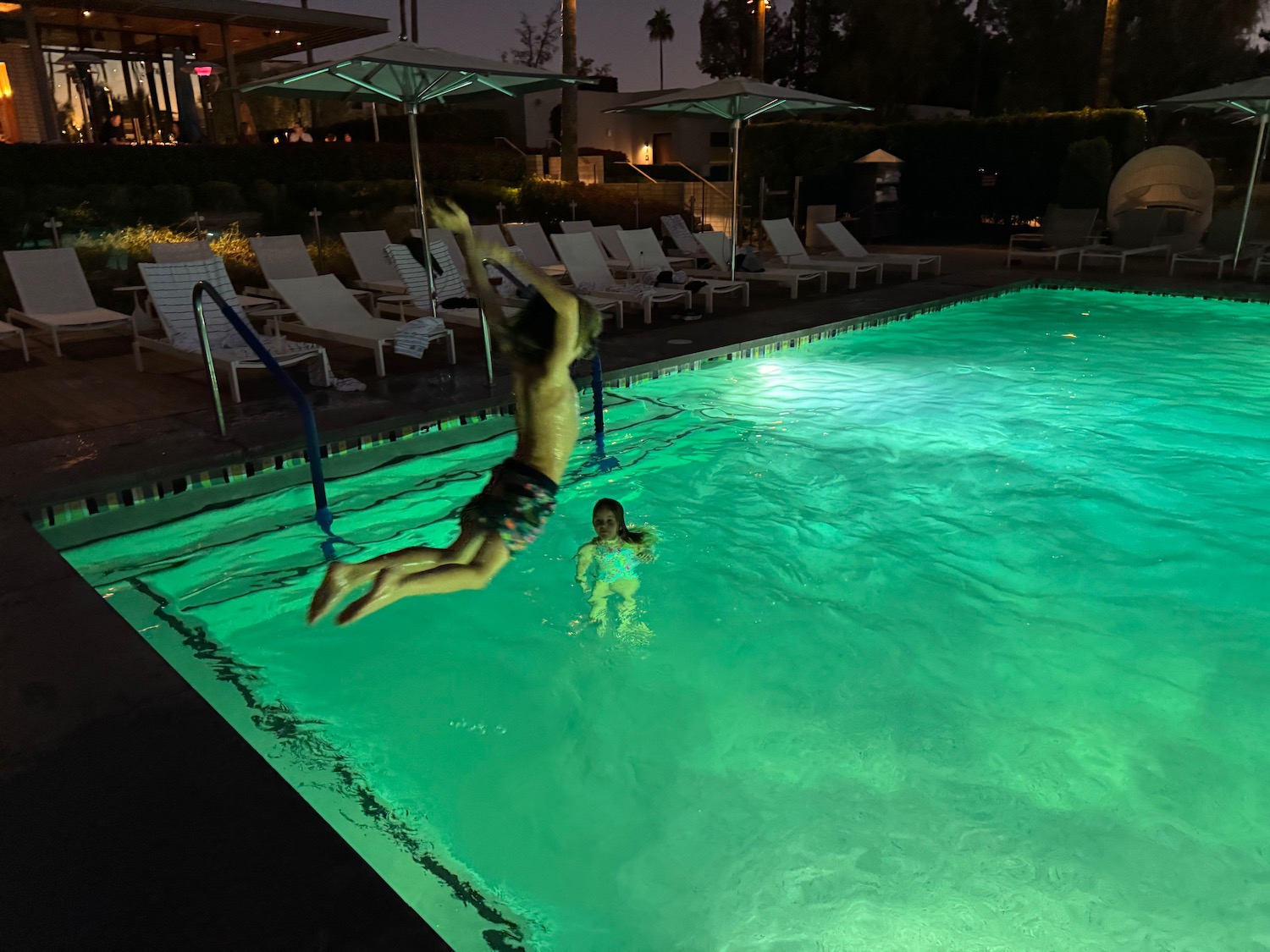 a person jumping into a pool at night