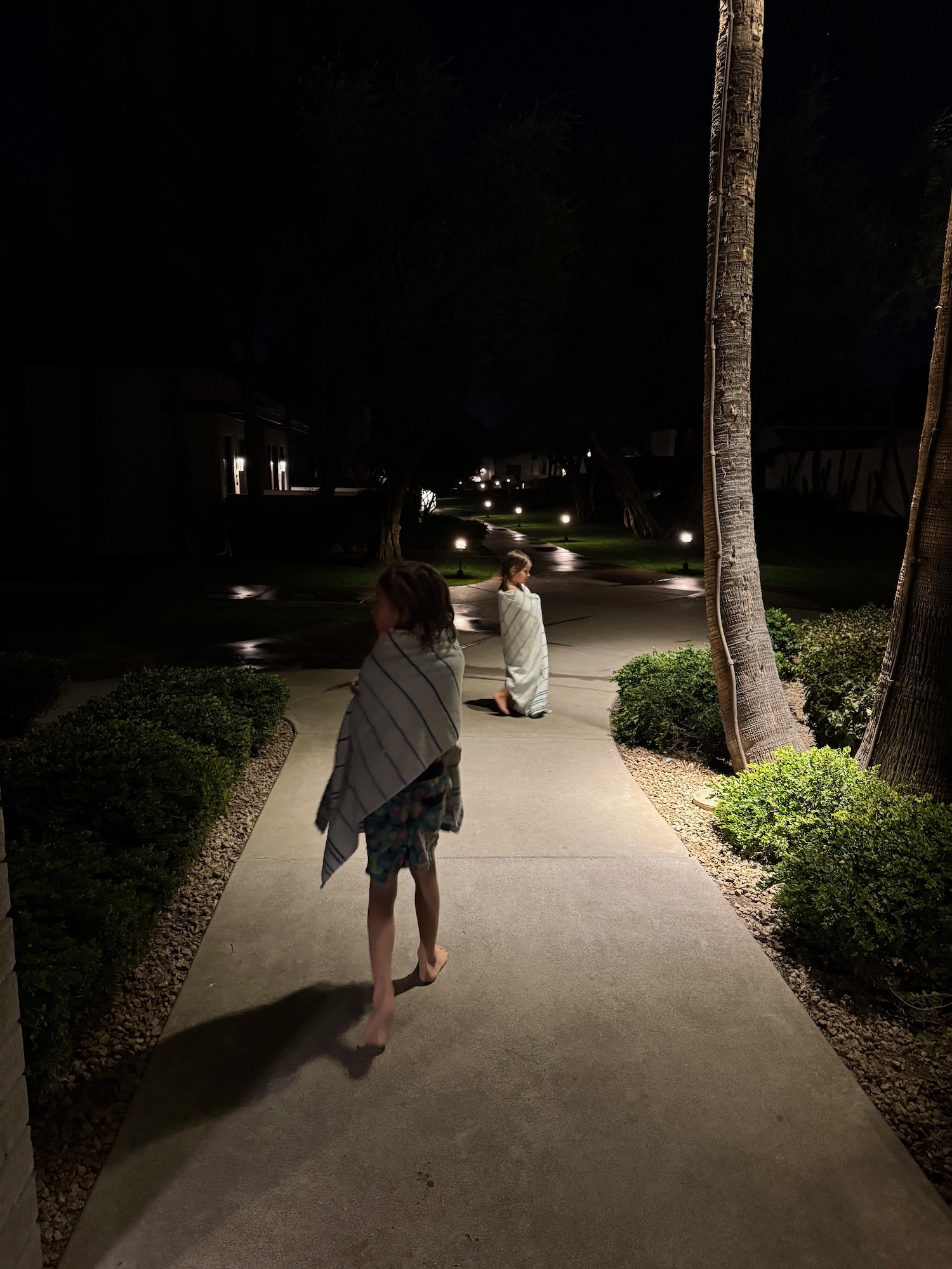 two children wrapped in blankets on a sidewalk