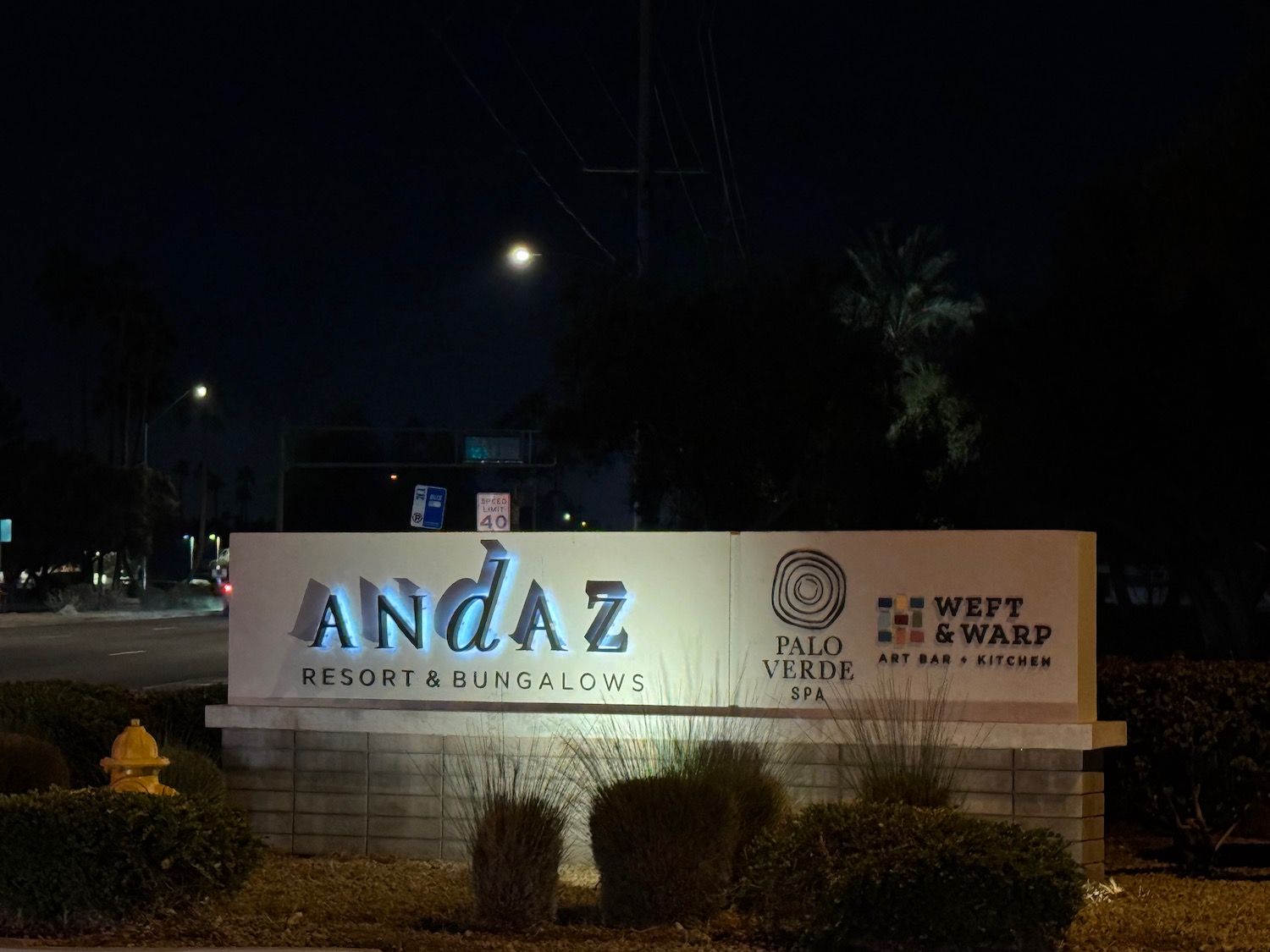 a sign at night with trees and street lights