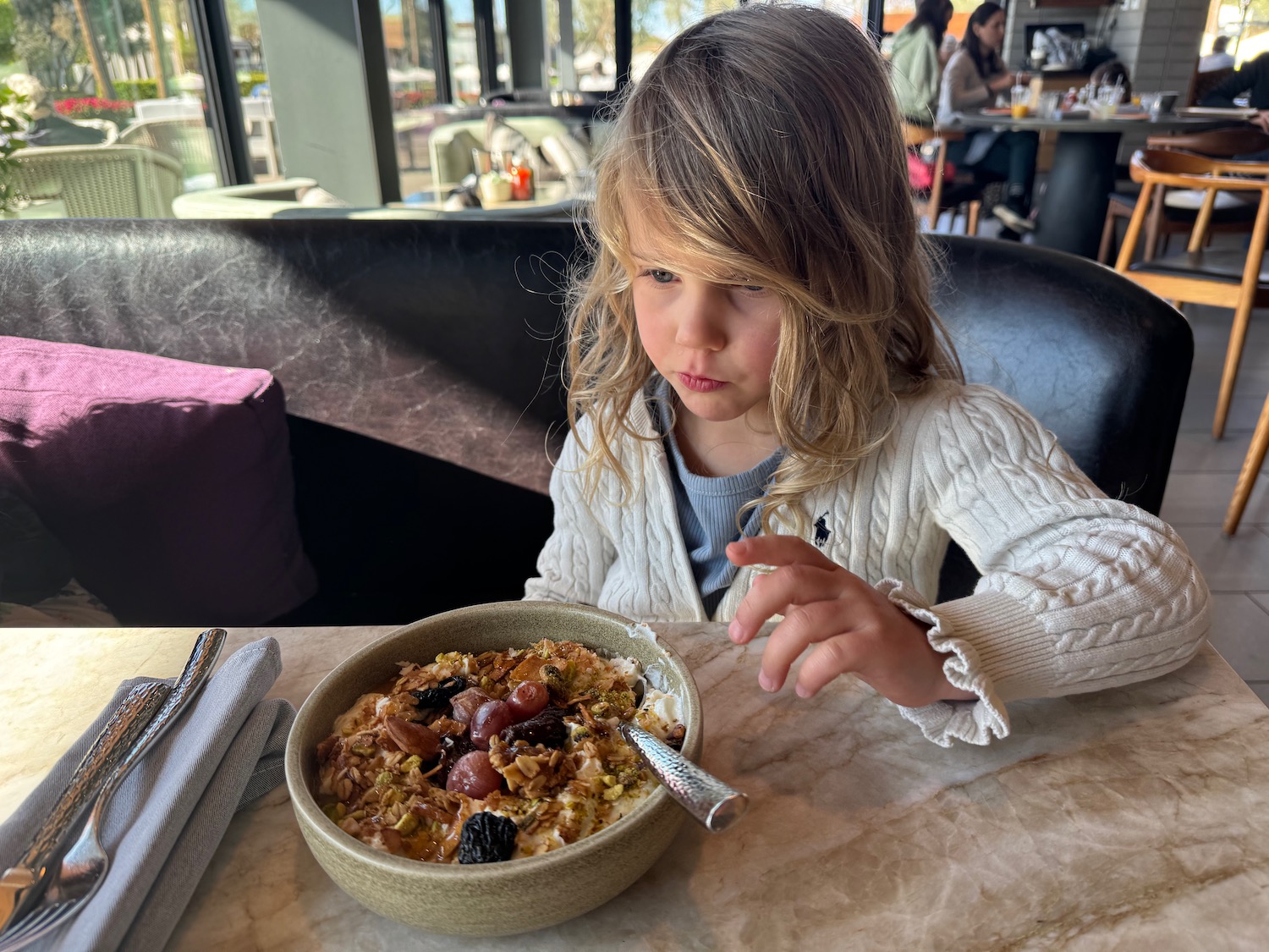 a girl sitting at a table with a bowl of food